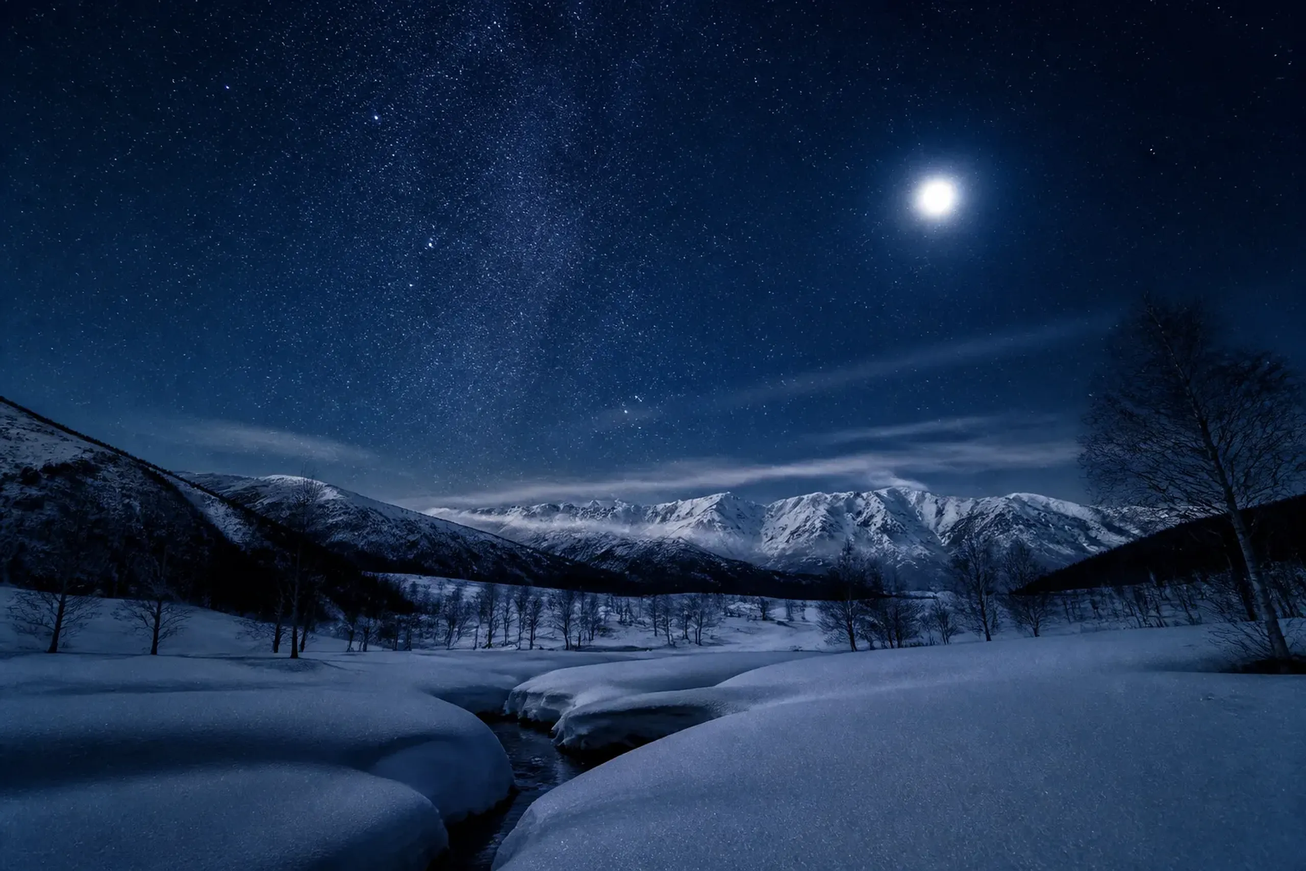 Snowy mountains under moonlight and stars illustrating how moon phase affects stargazing