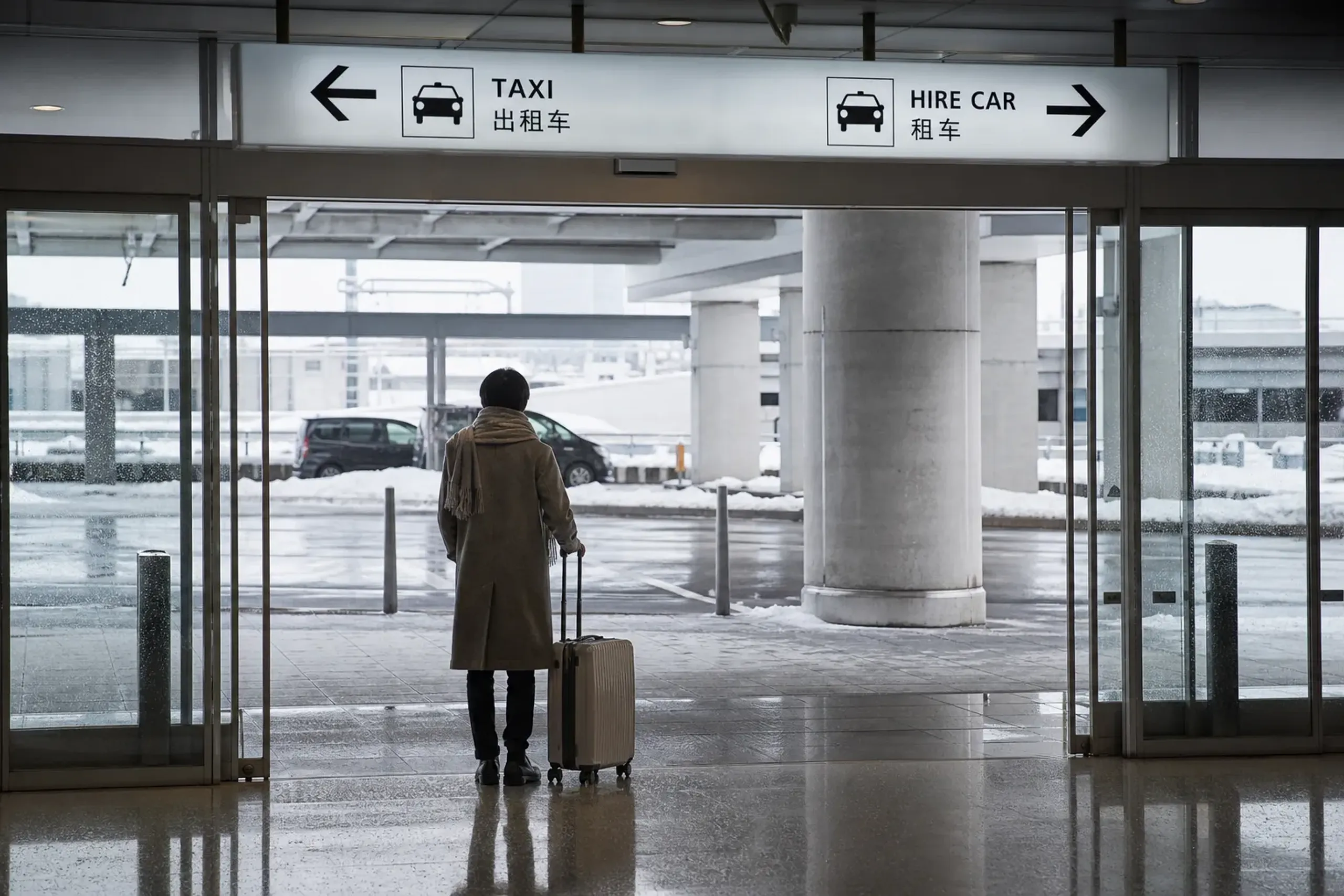 The arrivals hall exit at Haneda Airport with directional signage toward taxi and hire-car pickup lanes