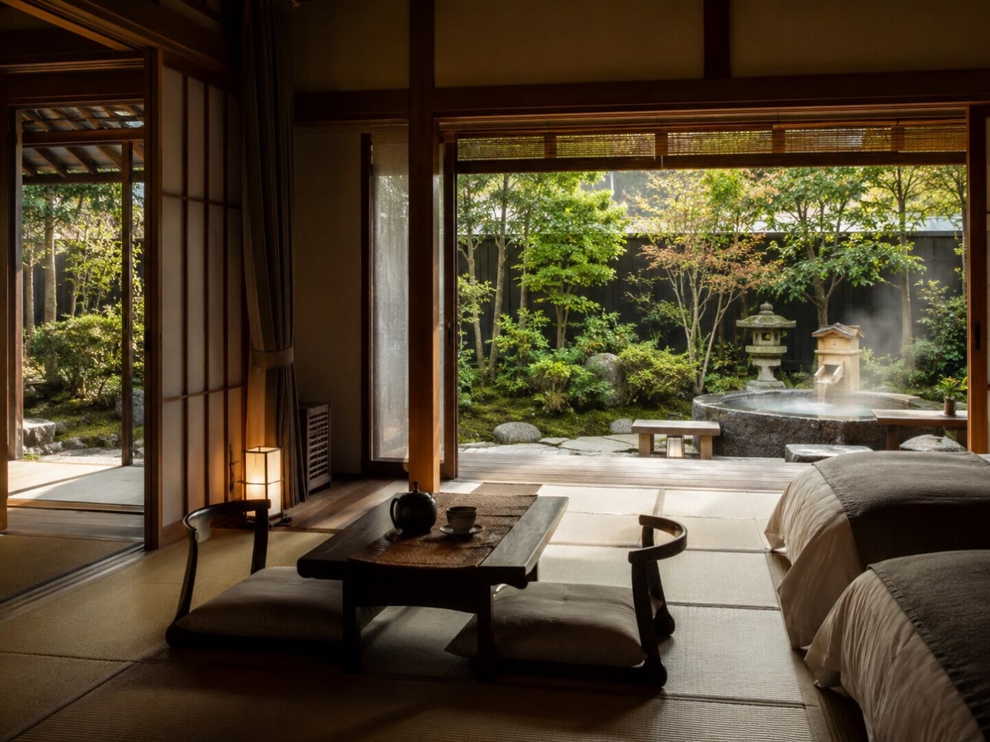 Japanese-style room with tatami floor, low table and floor cushions; opens to a garden with a stone lantern and steaming water basin.