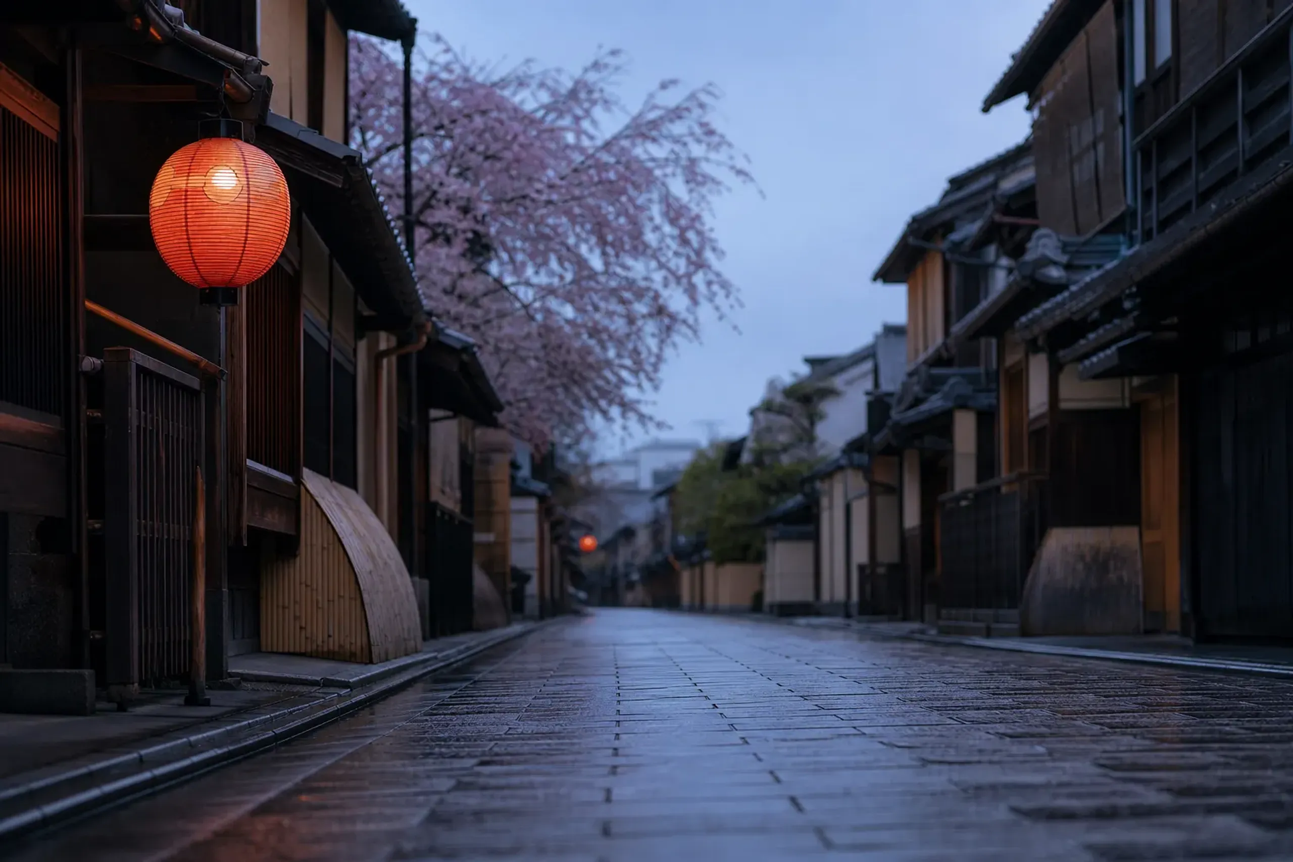 Quiet stone-paved lane lined with traditional wooden machiya townhouses in Kyoto's Gion district at dawn