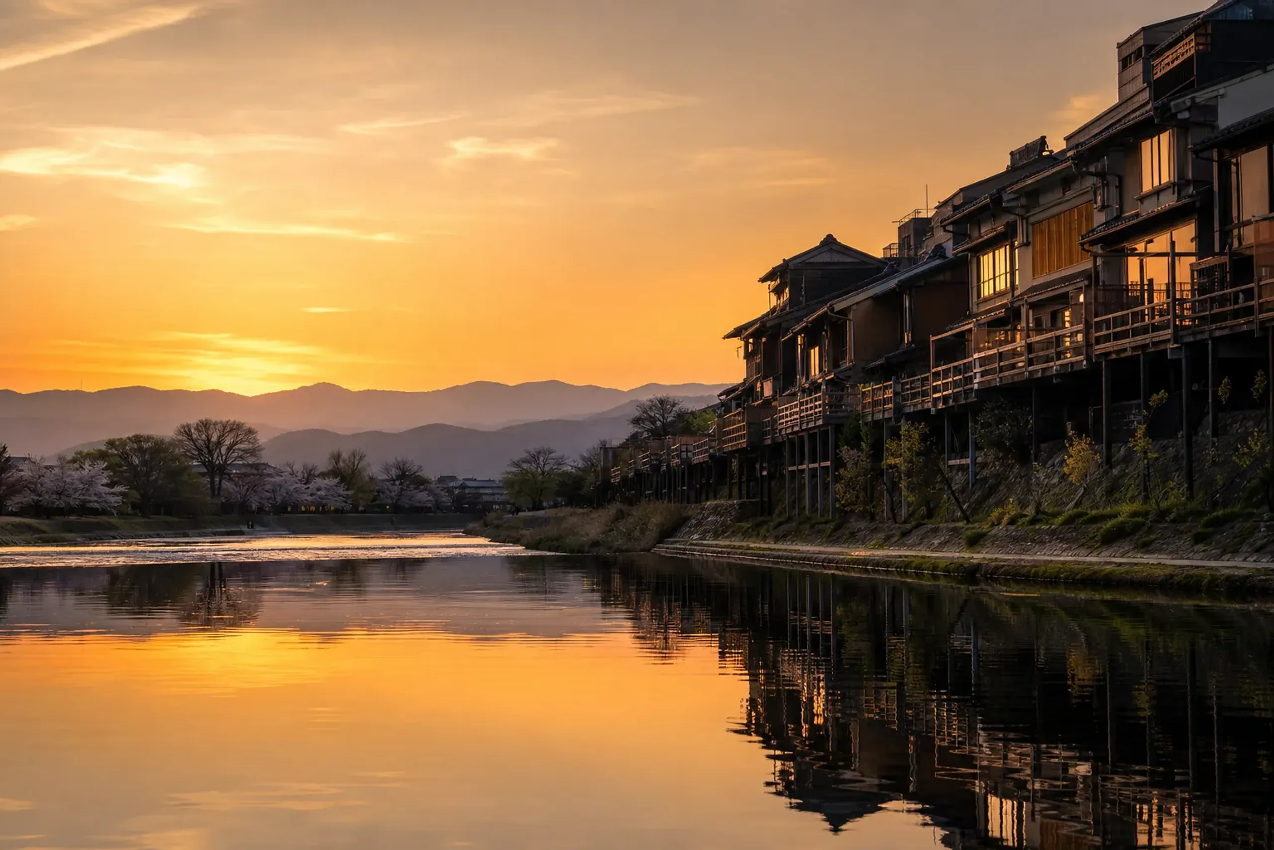 Kamo River in Kyoto at golden hour with traditional riverside buildings and the Higashiyama hills beyond