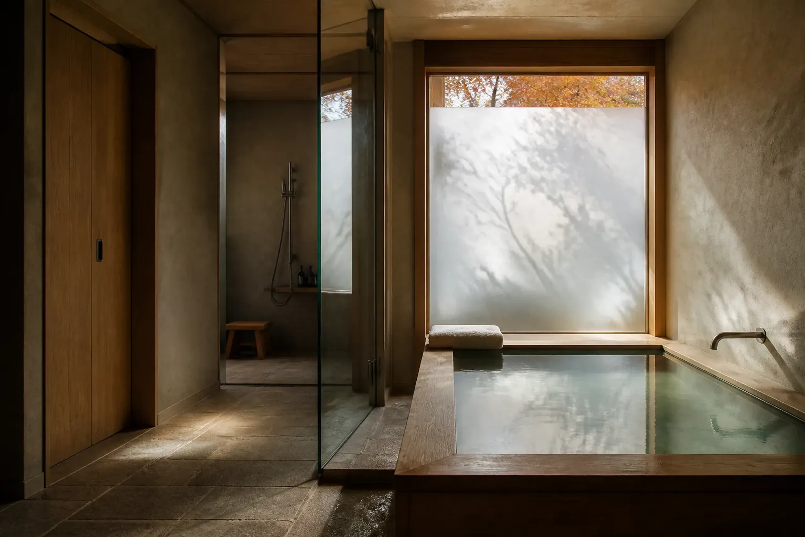 Japanese hotel bathroom with soaking tub, separate toilet, and glass partition