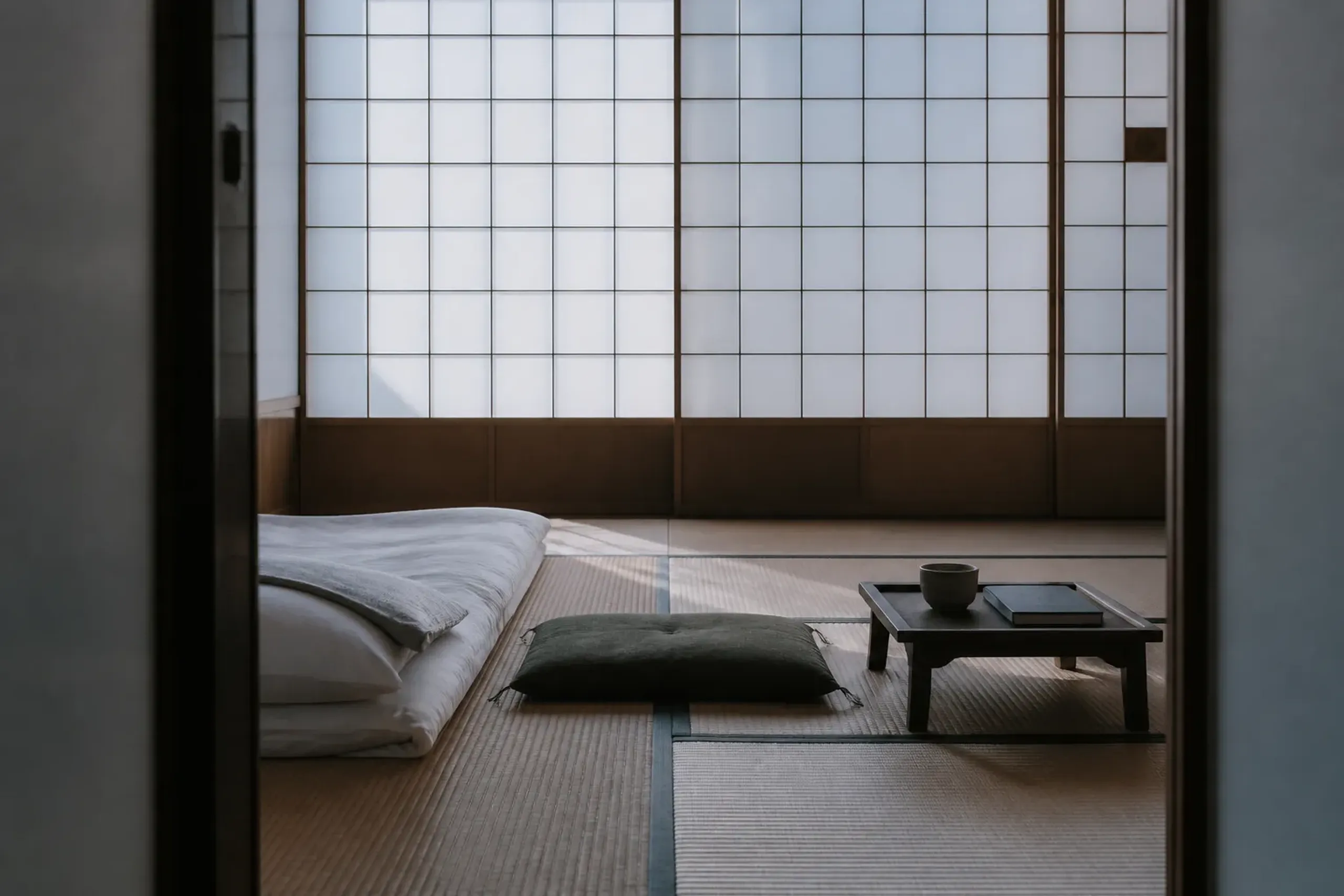 Tatami room with a folded futon and shoji screens showing the simple lodging style of a temple stay