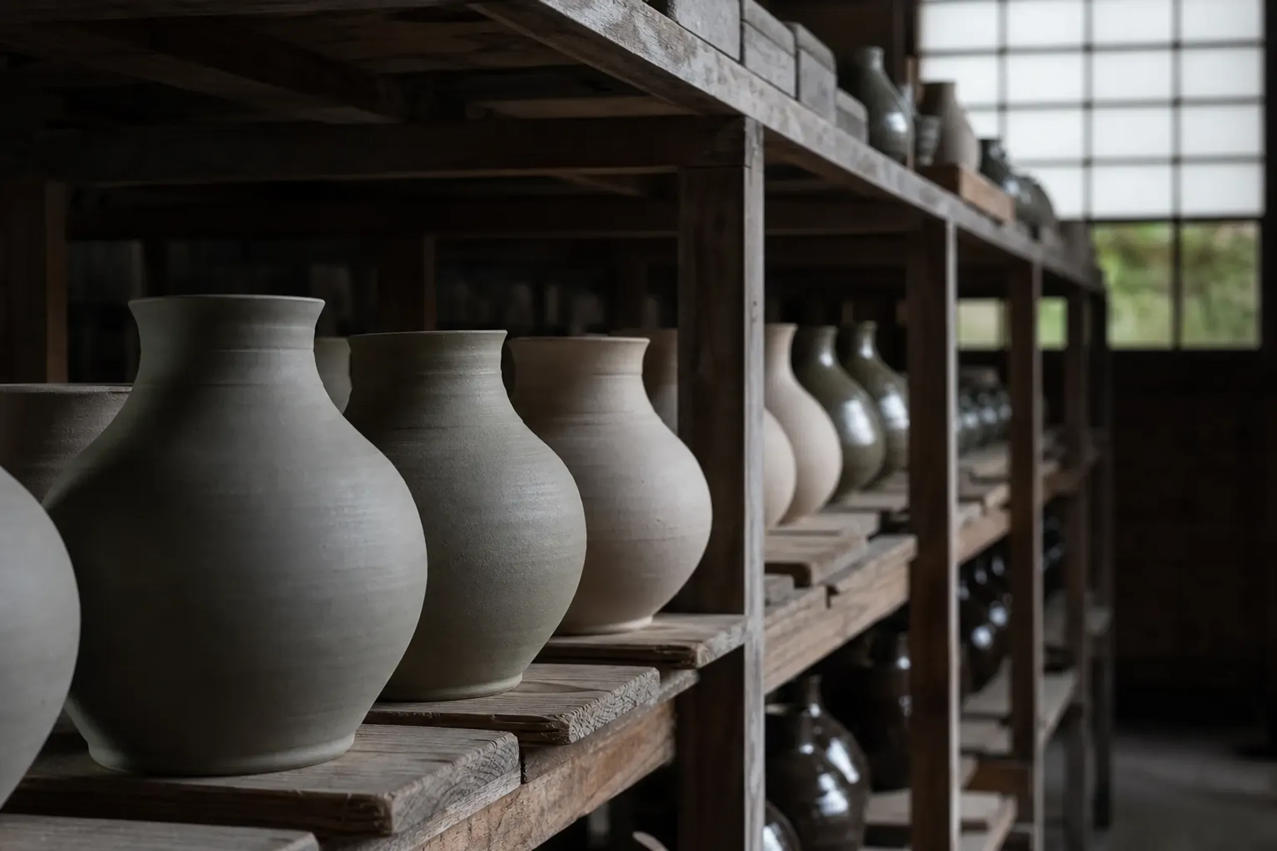 Handmade pieces at various stages of production resting on drying racks in a Japanese atelier