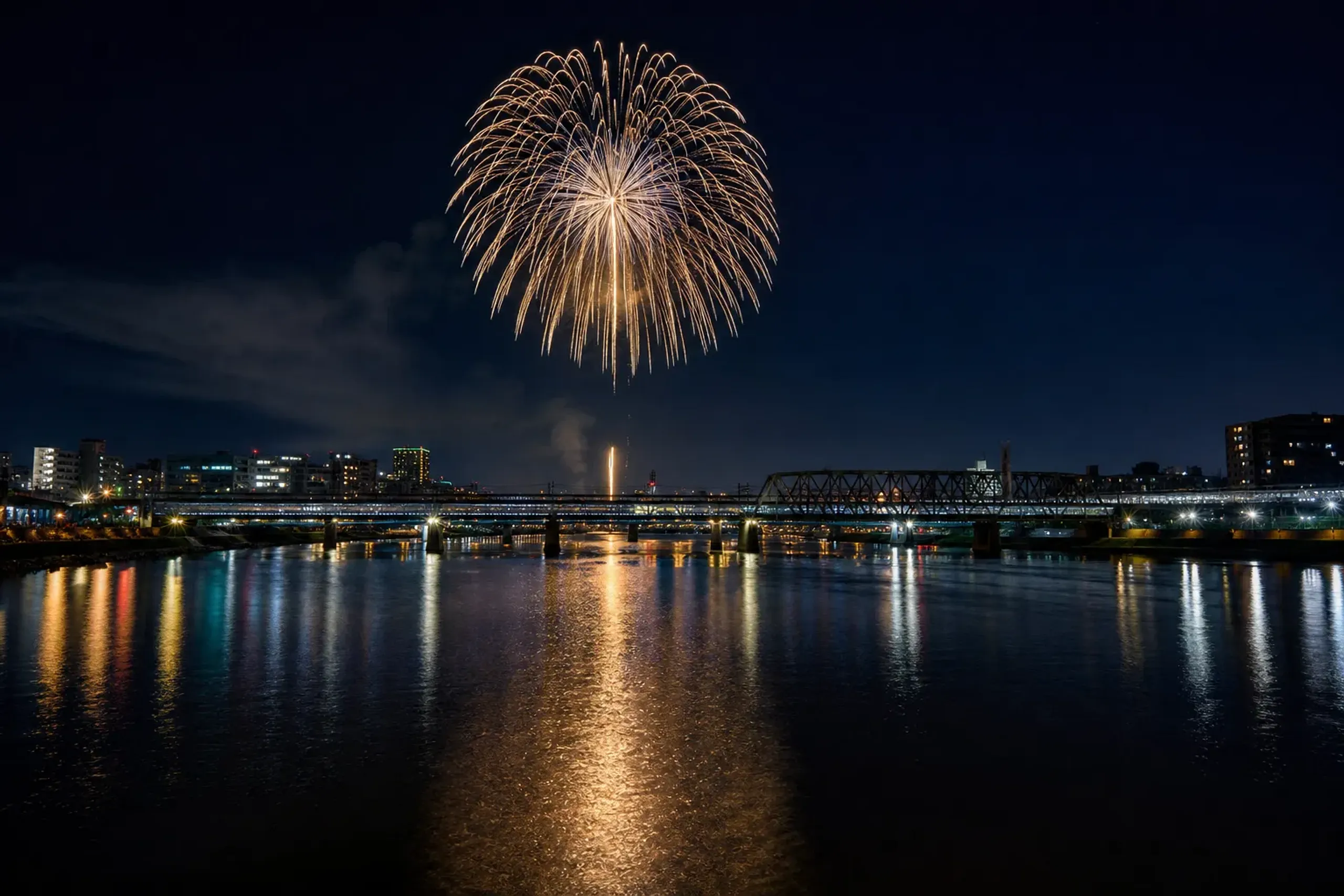 Fireworks over Tokyo’s Sumida River at night with reflections on the water