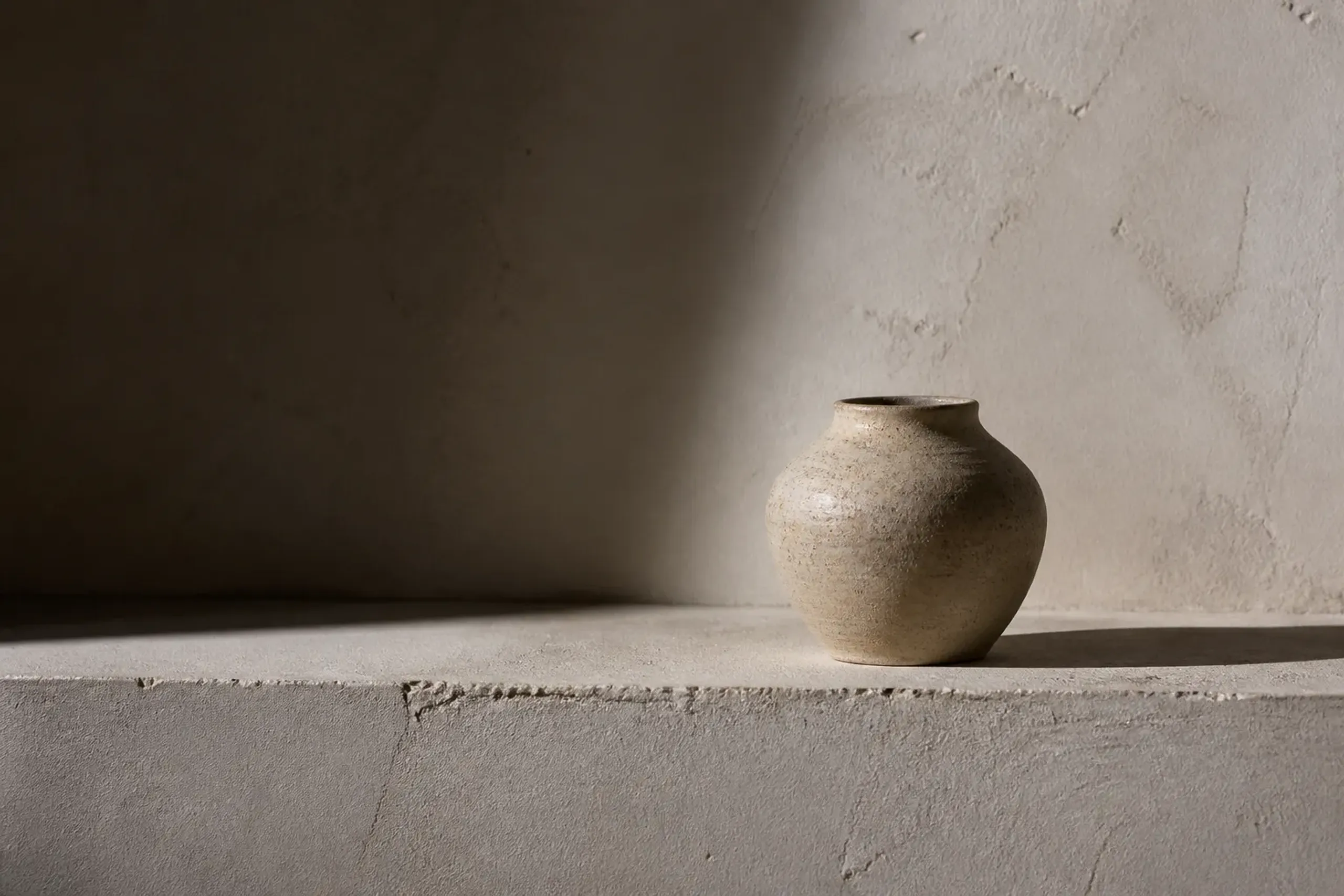 Unglazed ceramic vessel on a plaster shelf in a minimalist Tokyo gallery lit by soft autumn daylight