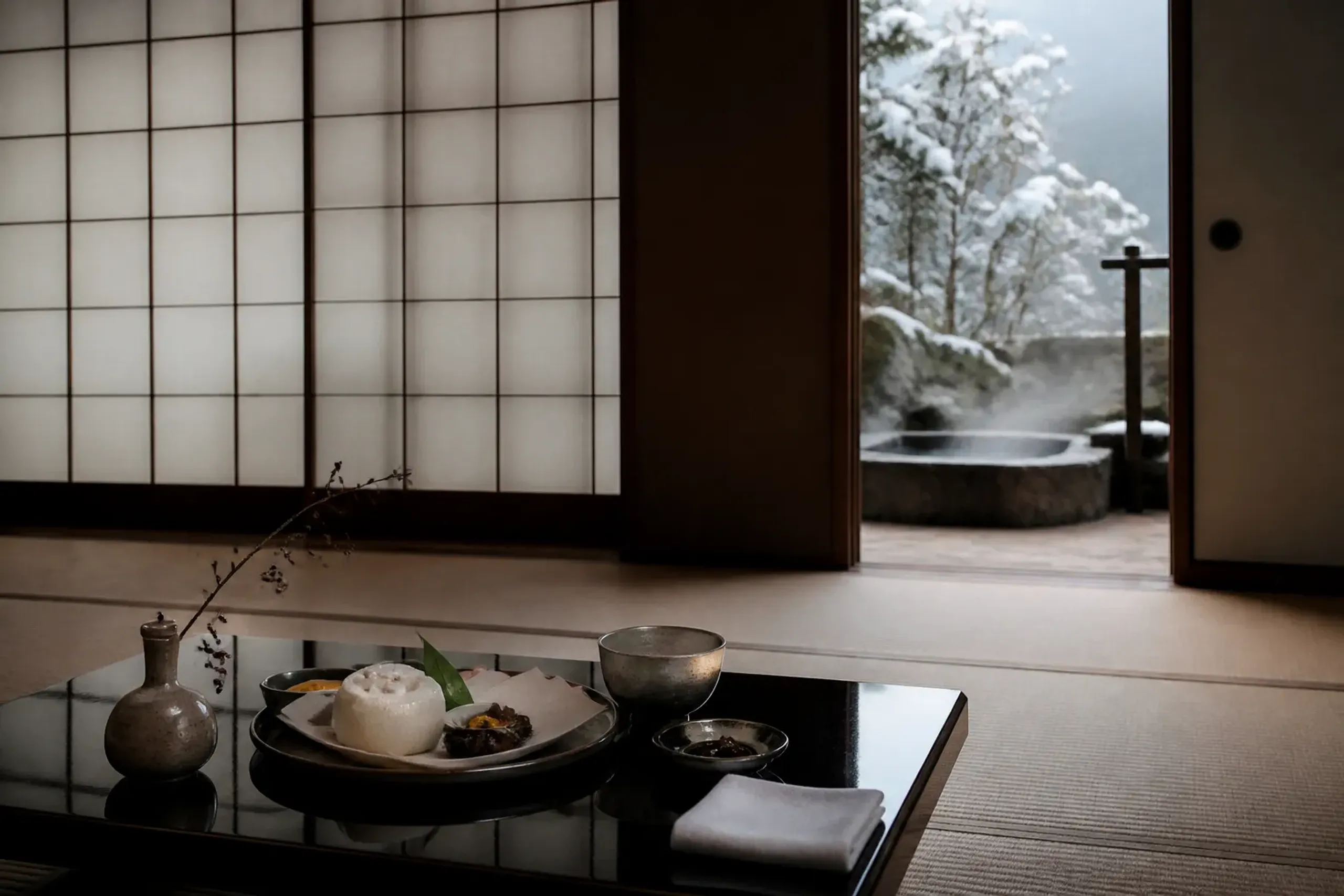 Ryokan tatami room set for kaiseki with shoji screens and a glimpse of a private bath