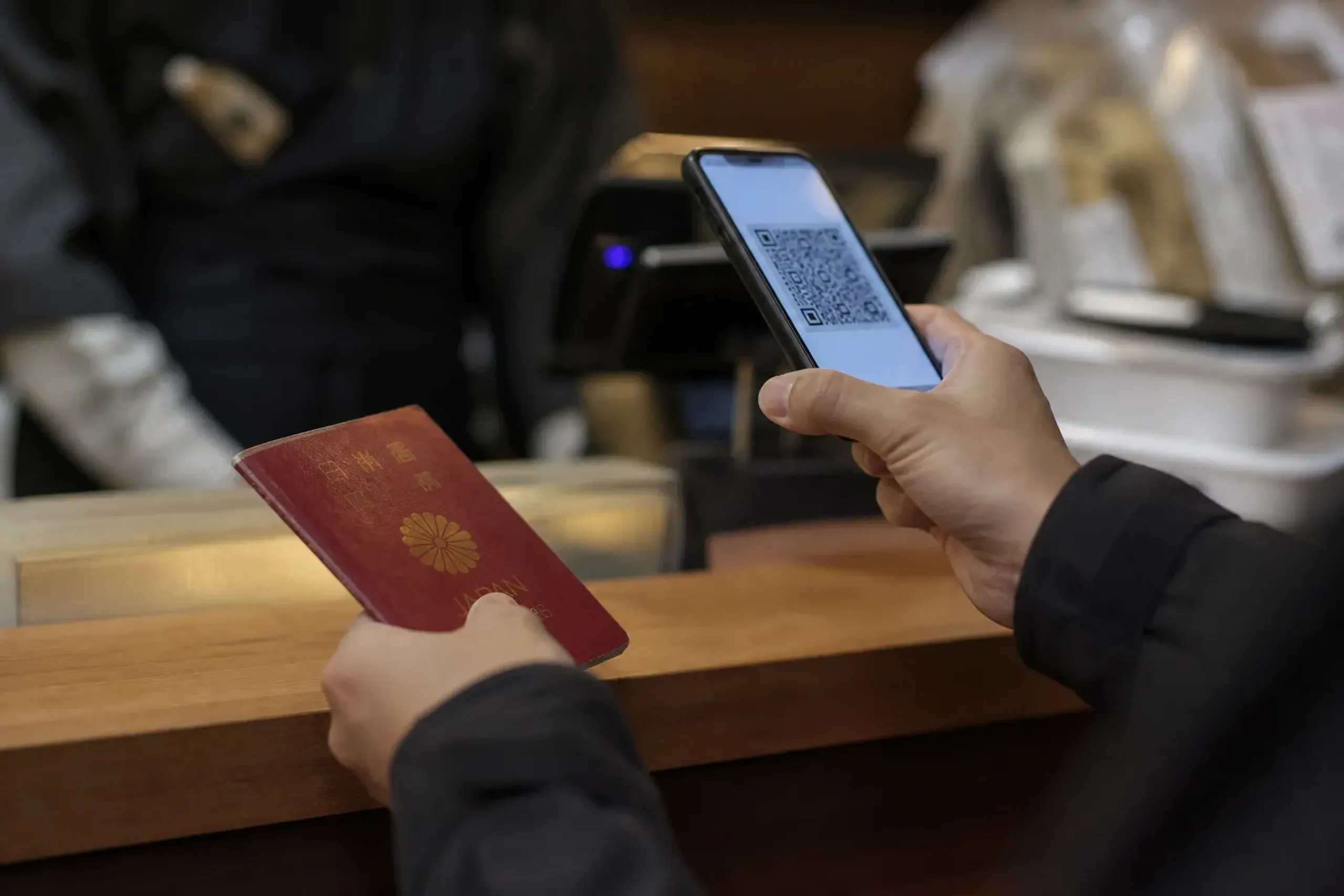 Traveler holding passport and phone with QR code at a tax-free counter in Japan