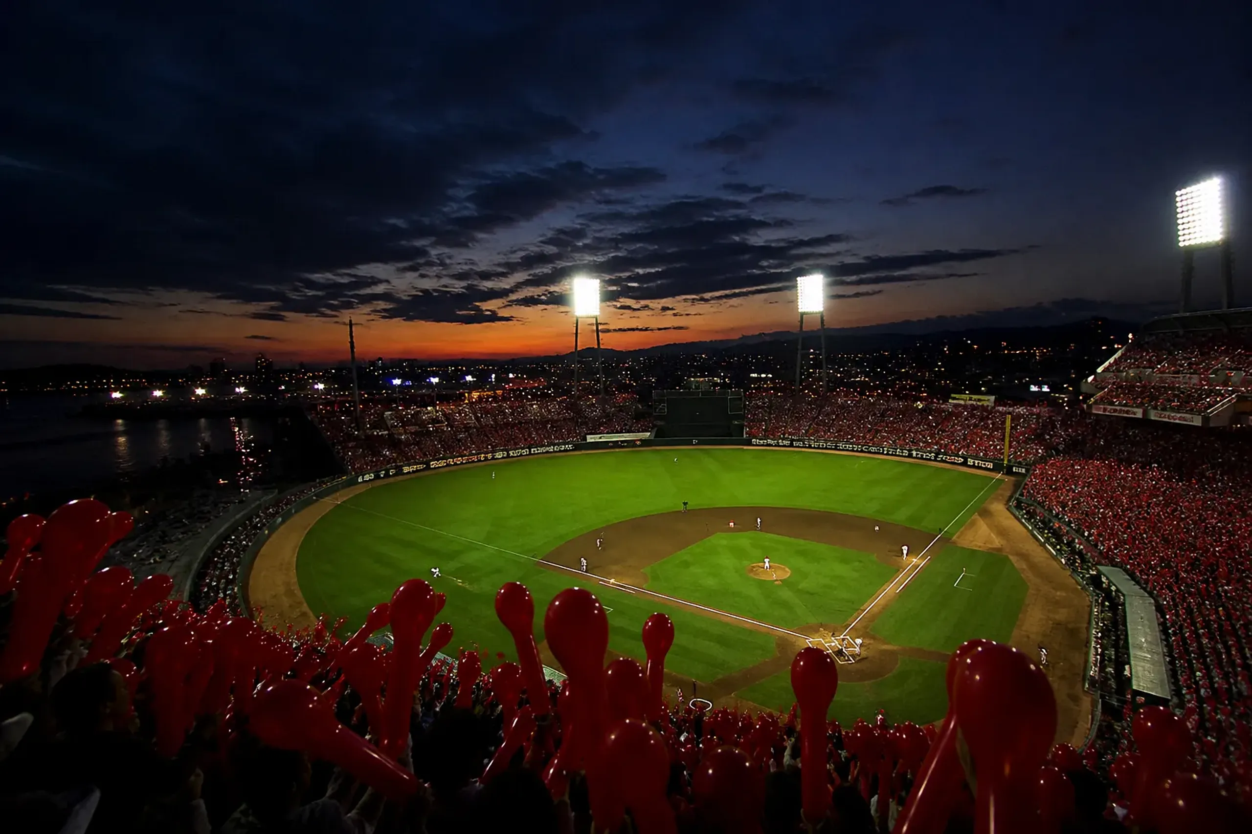 the illuminated baseball field and grandstands of MAZDA Zoom-Zoom Stadium Hiroshima at dusk during a game