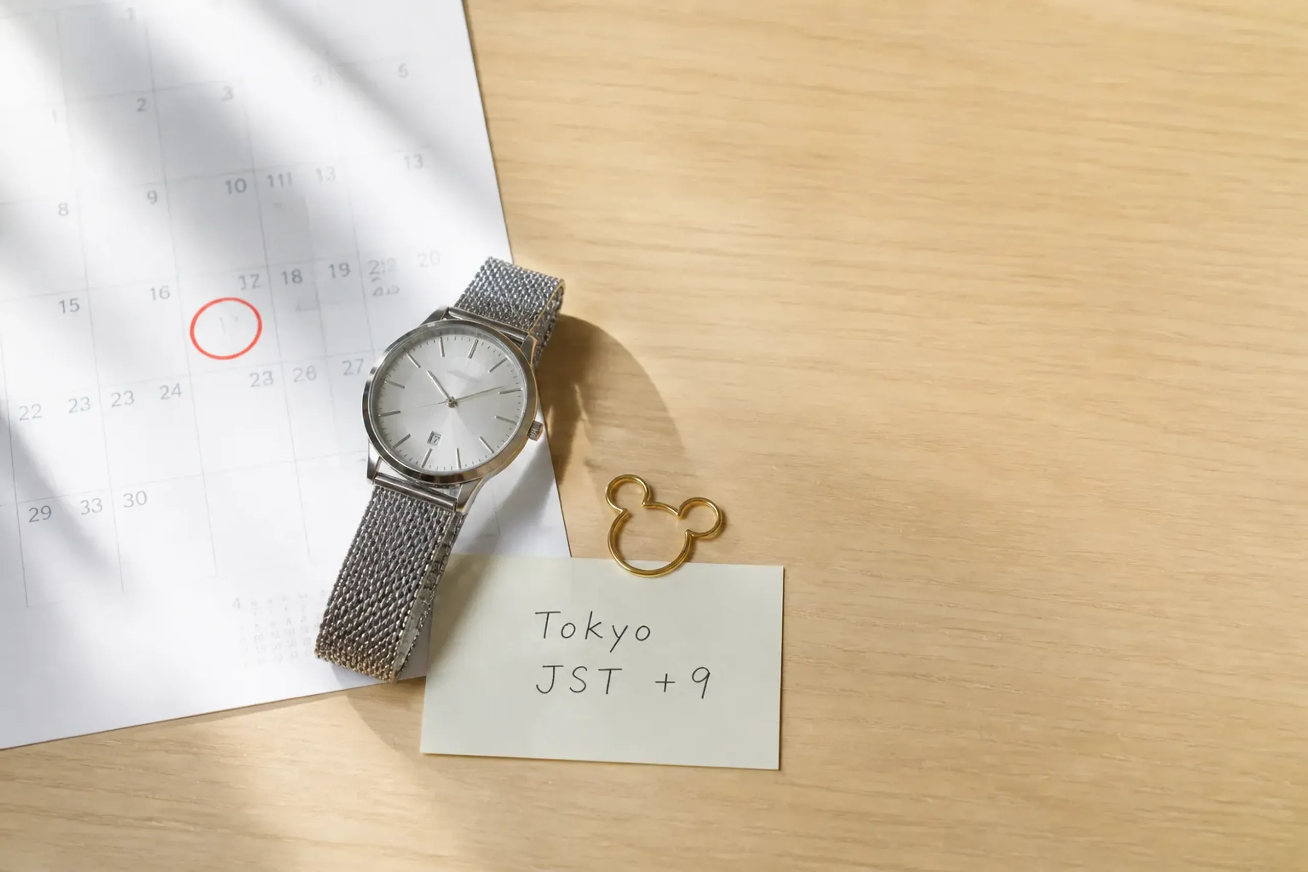 Watch and calendar on a desk representing a strict booking deadline in Japan Standard Time