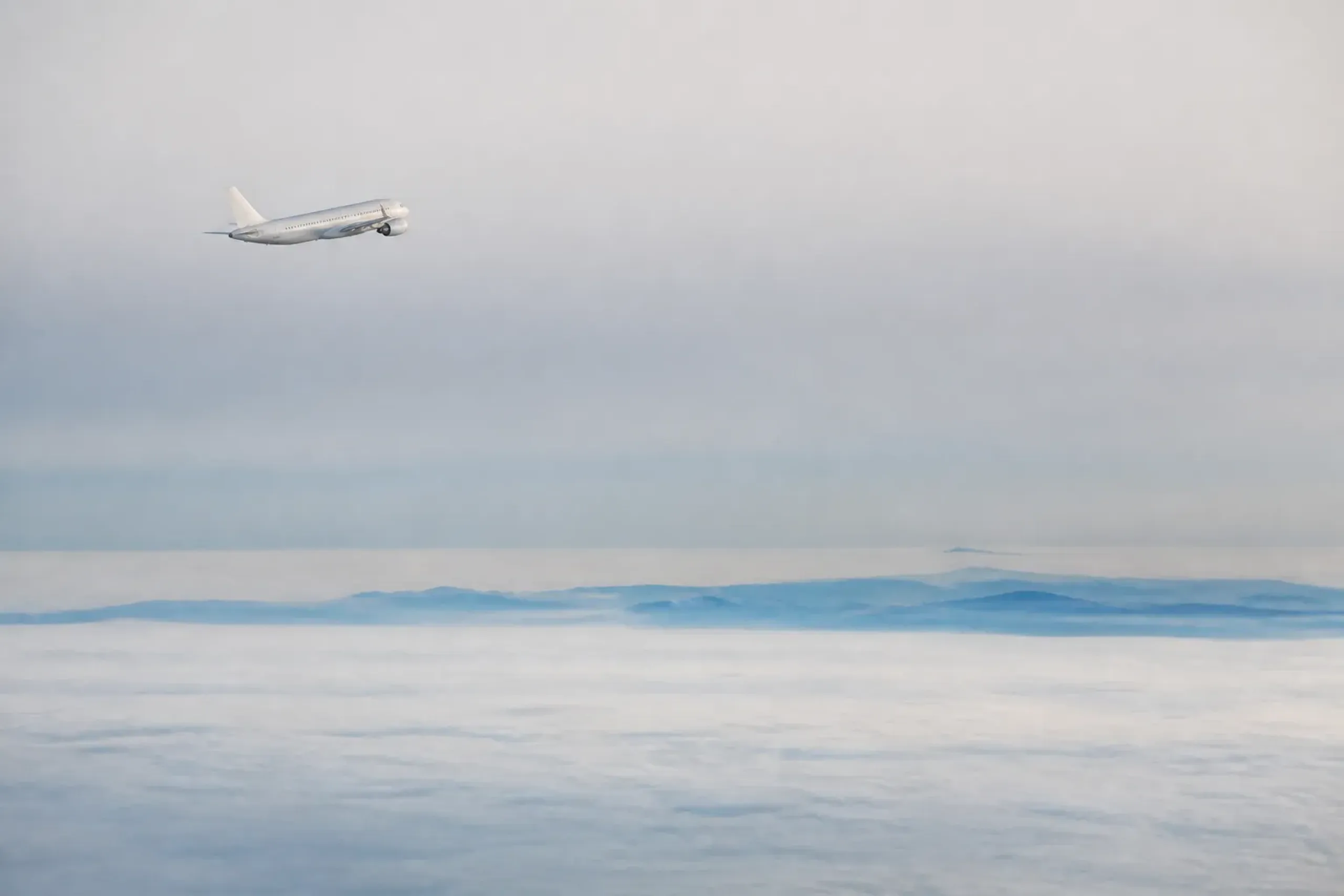 A domestic Japanese airliner cruising above the cloud layer over the mountainous Japanese archipelago, connecting distant regions like Hokkaido and Okinawa that reshape the travel map