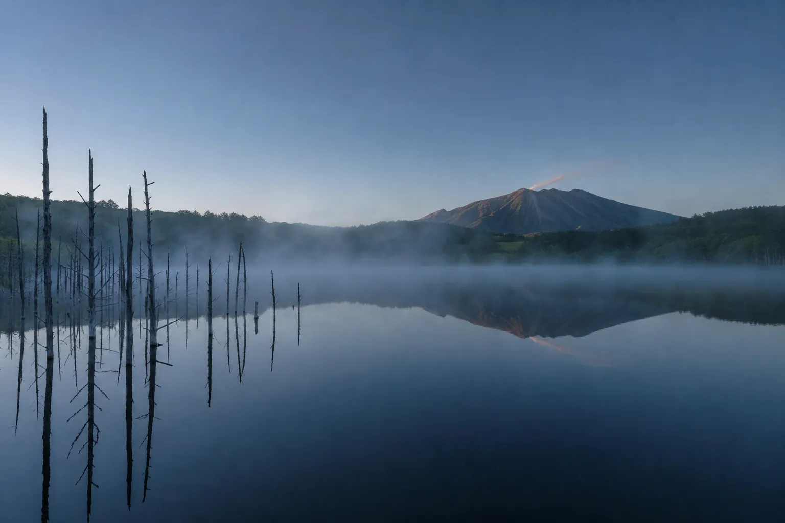 Morning mist over Taisho Pond in Kamikochi with Mount Yake reflected in still water