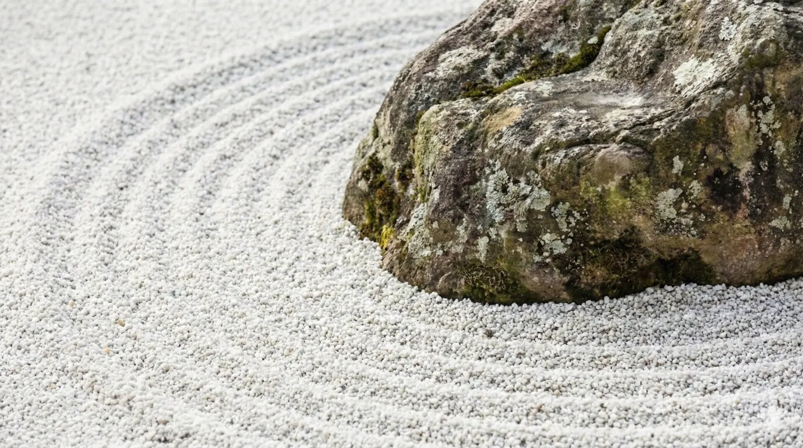 A serene Japanese rock garden (karesansui) with raked white sand and weathered stones.