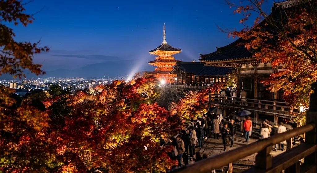 Kiyomizu-dera Temple's iconic pagoda and wooden structures glow under brilliant night illumination, surrounded by radiant autumn leaves against a twilight sky.