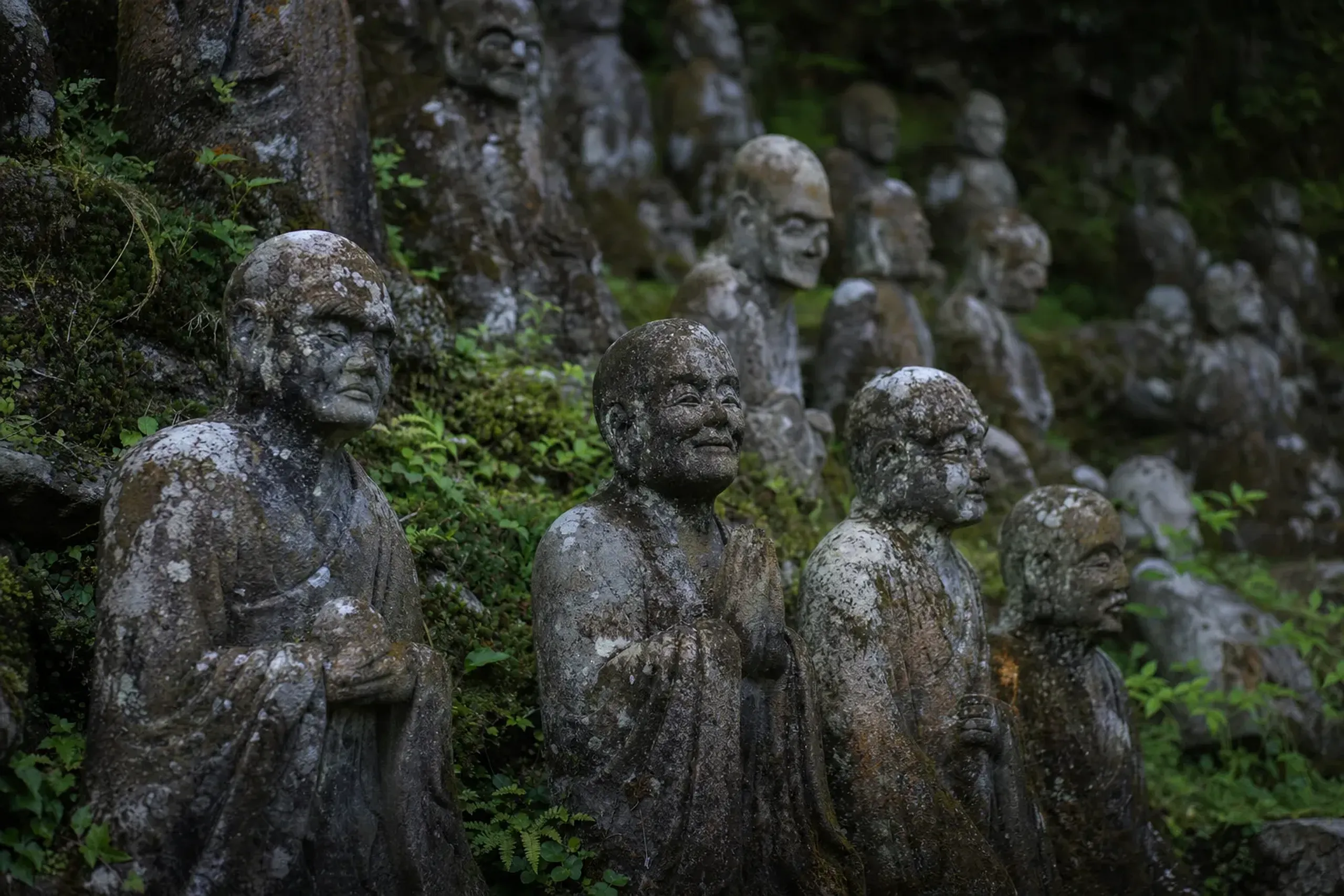 The 500 weathered stone arhat statues, the Gohyaku Rakan, standing quietly among the mossy greenery of Mifuneyama Rakuen's grounds