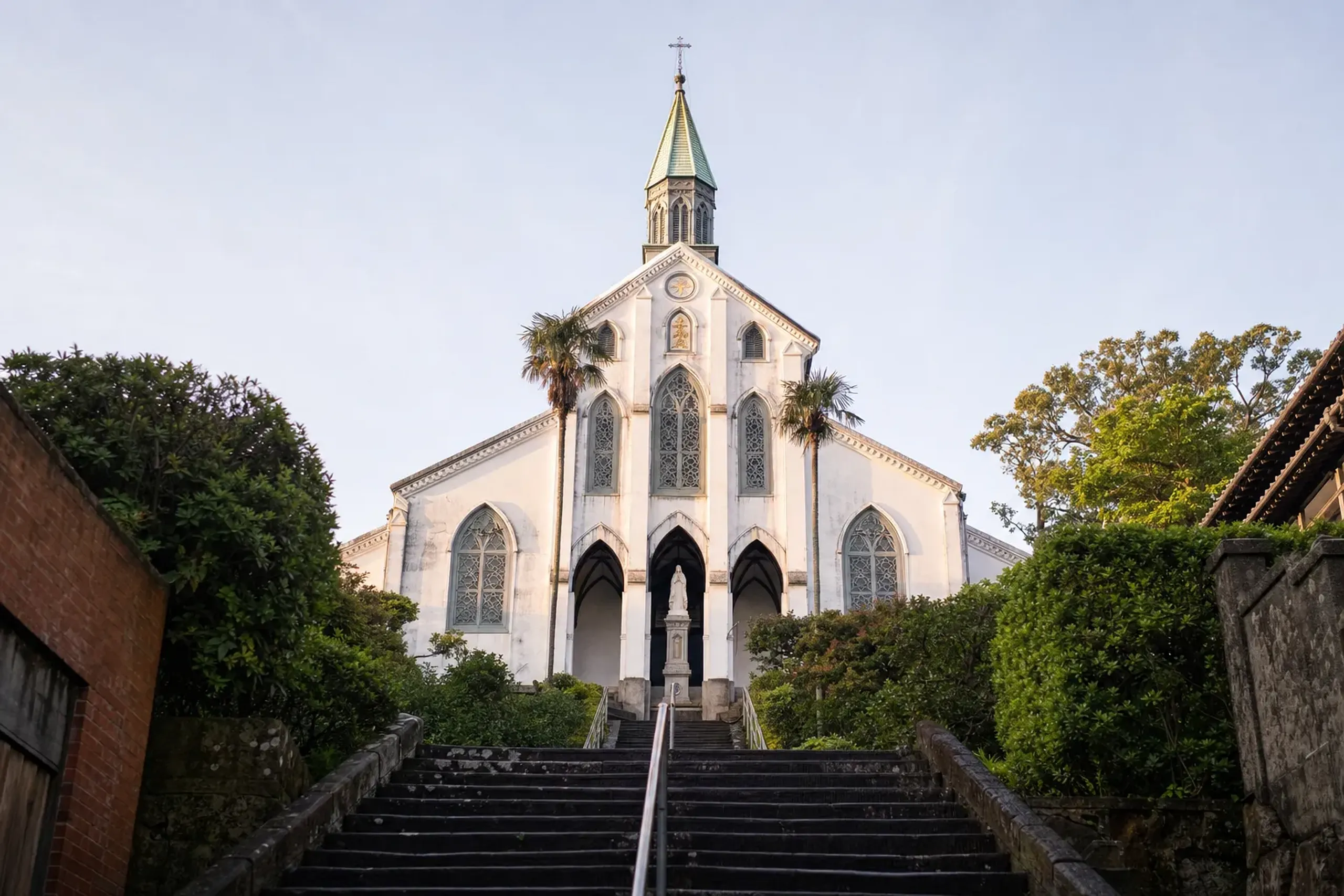 The white stone facade and arched entrance of Ōura Cathedral in Nagasaki, completed in 1864, the oldest Gothic-style church in Japan and a designated National Treasure