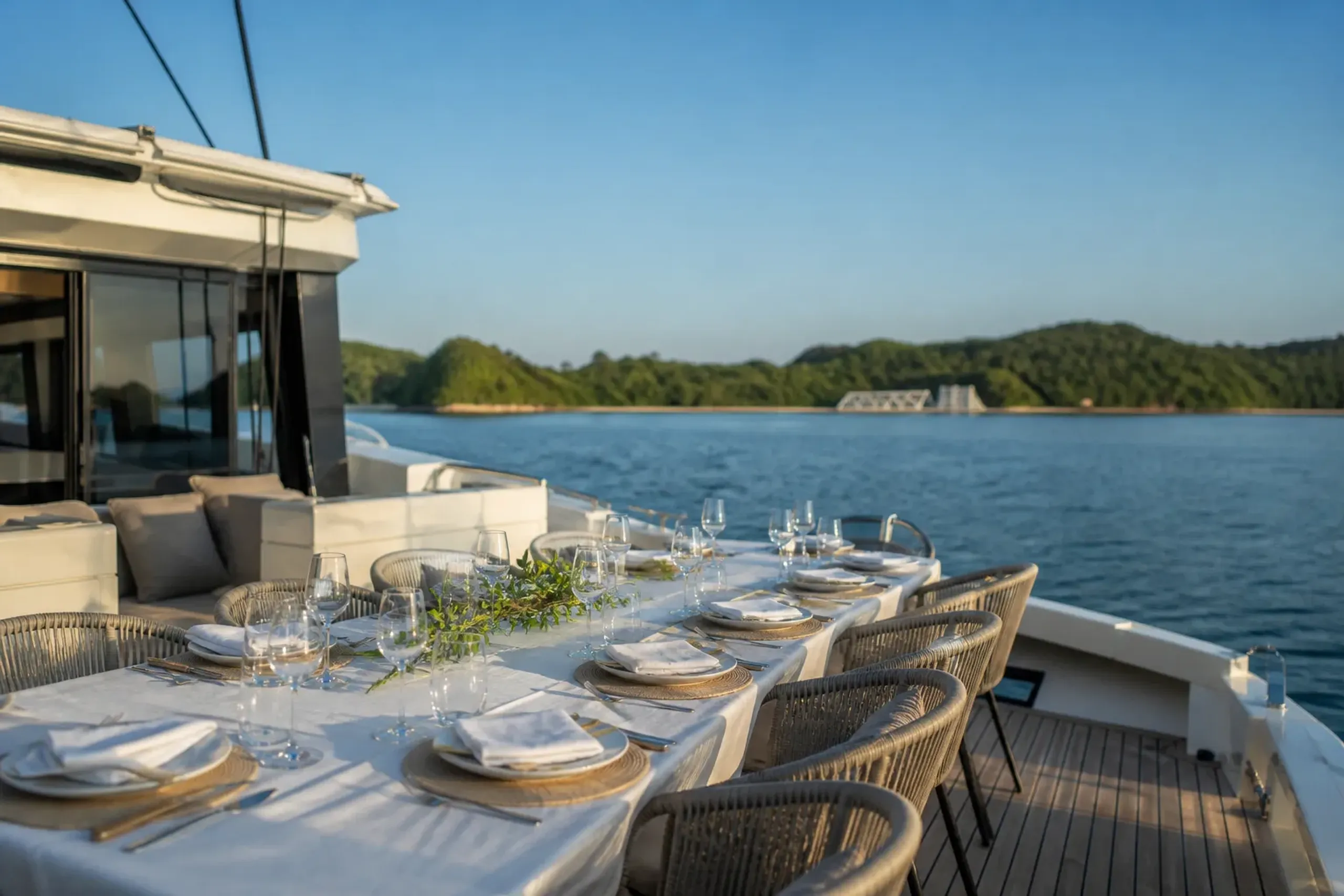 A twelve-metre twin-hull catamaran with an open-deck dining table set for eight, at anchor off Miyanoura port on Naoshima