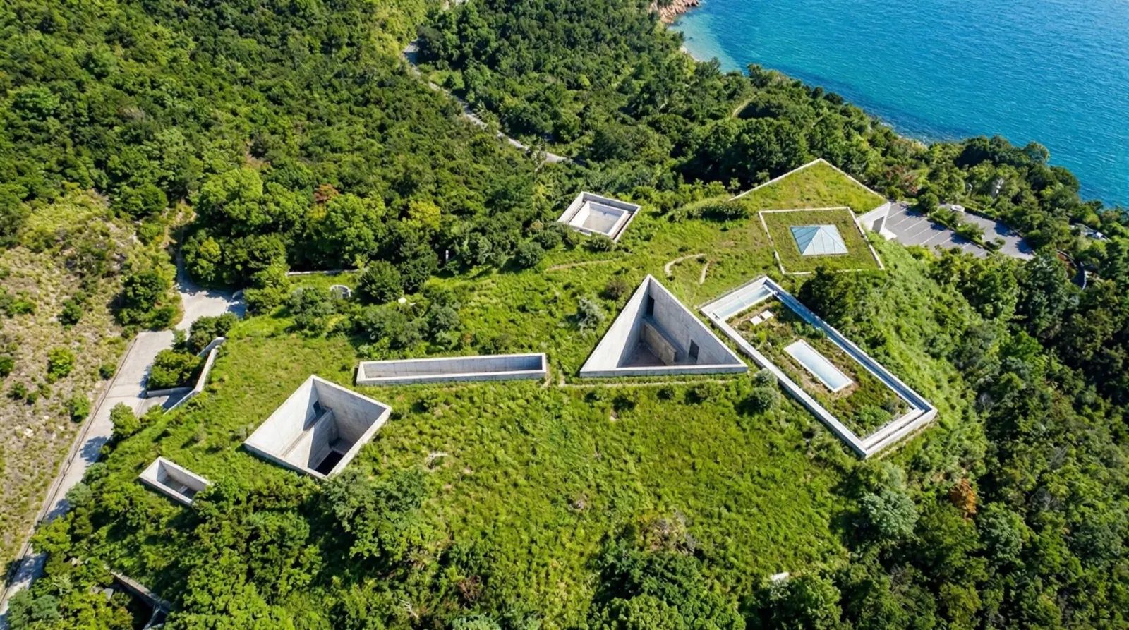 An aerial view of geometric concrete shapes built into a green hillside on the island of Naoshima.
