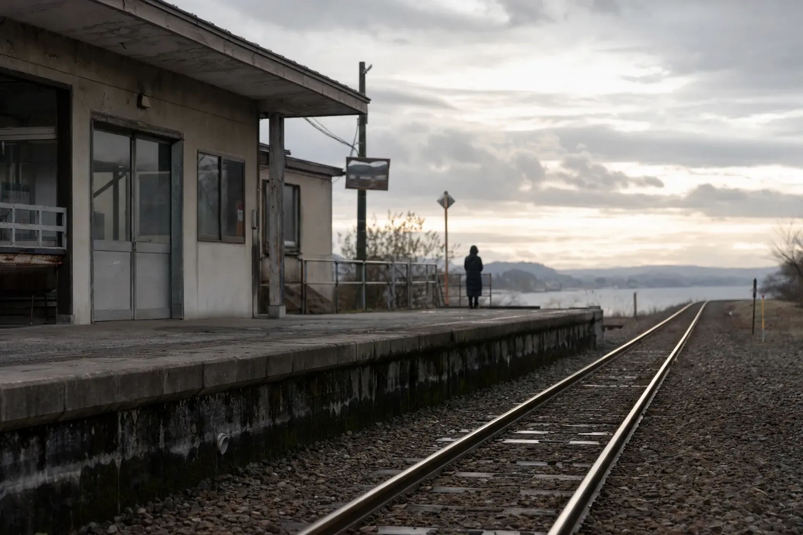 The platform and station building of Omagari Station in Daisen, Akita, with rail lines leading toward the fireworks riverbank