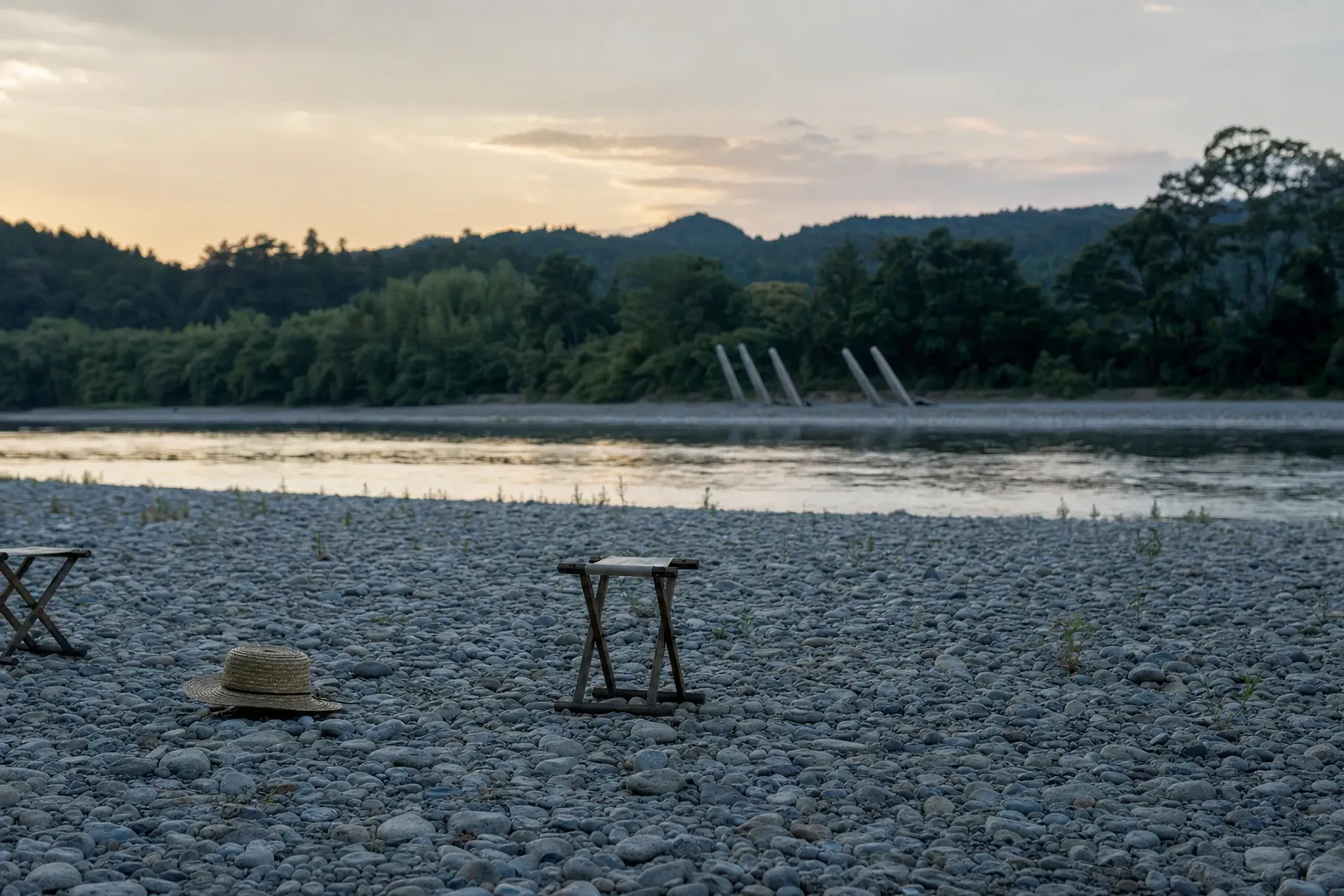 The wide gravel banks of the Omono River in Daisen at late-August dusk, viewing ground facing the far-bank launch site