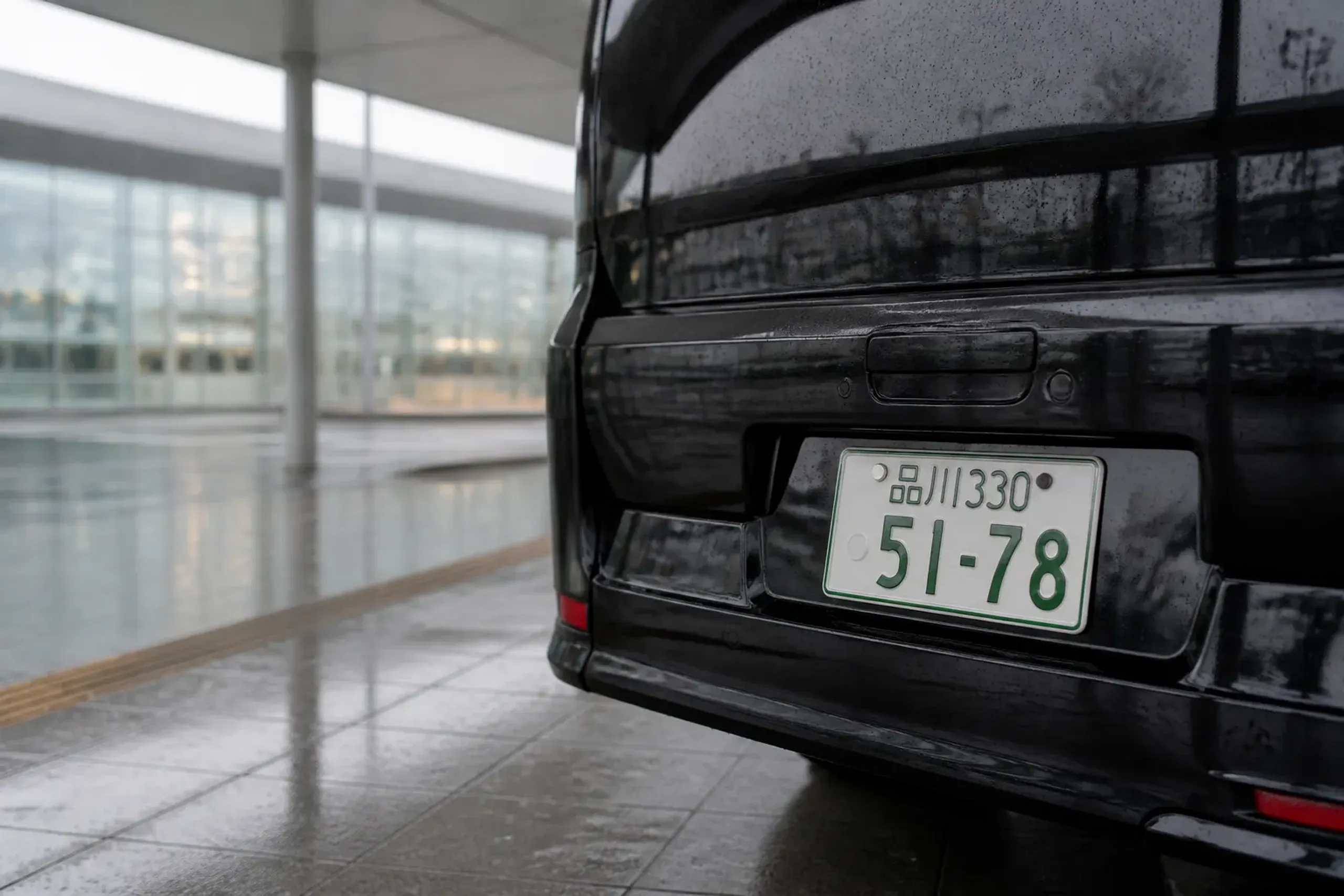 Green Japanese number plate on a licensed black chauffeur van at a Tokyo airport terminal