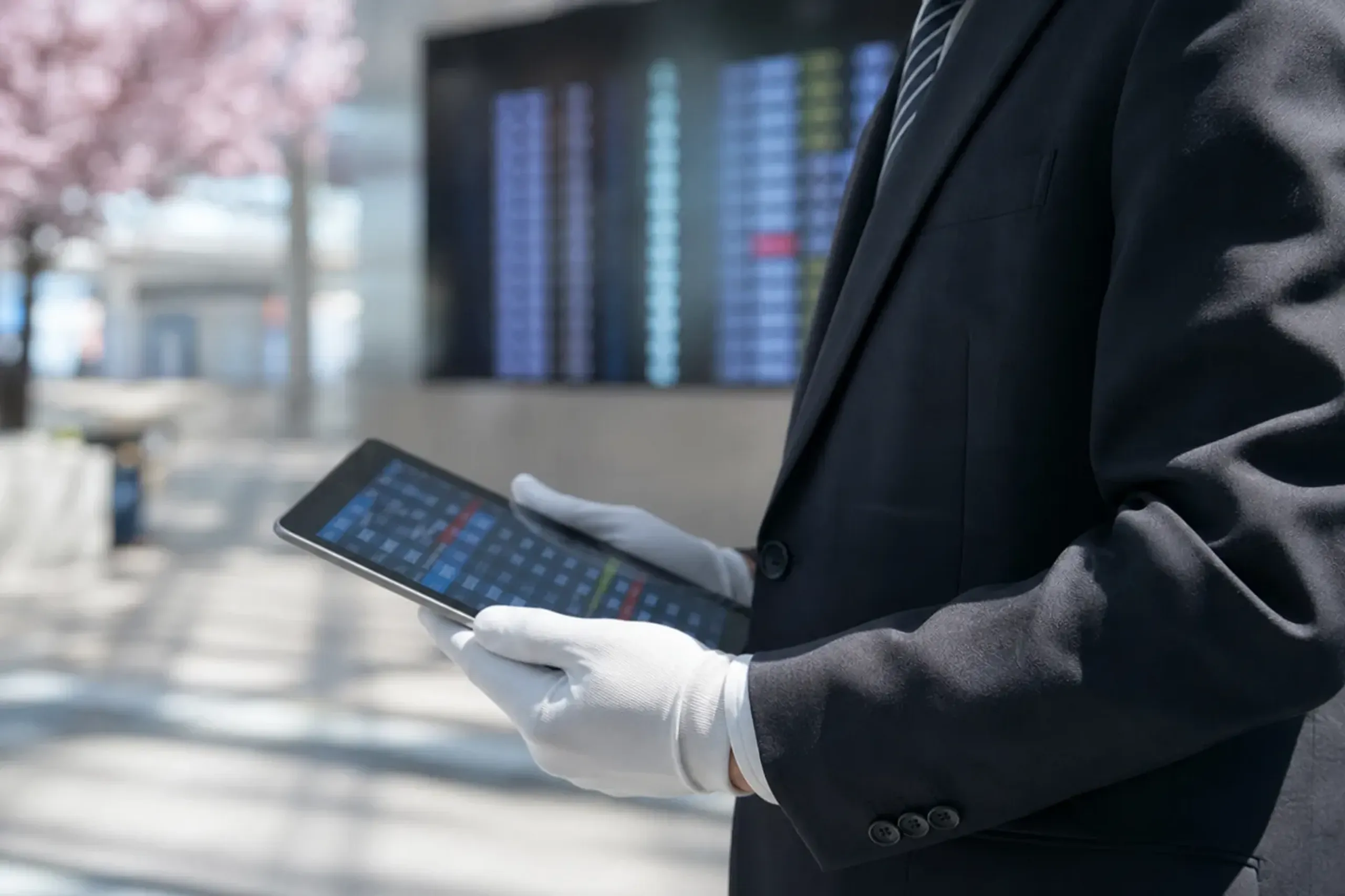 Chauffeur monitoring flight status near an airport arrivals information board