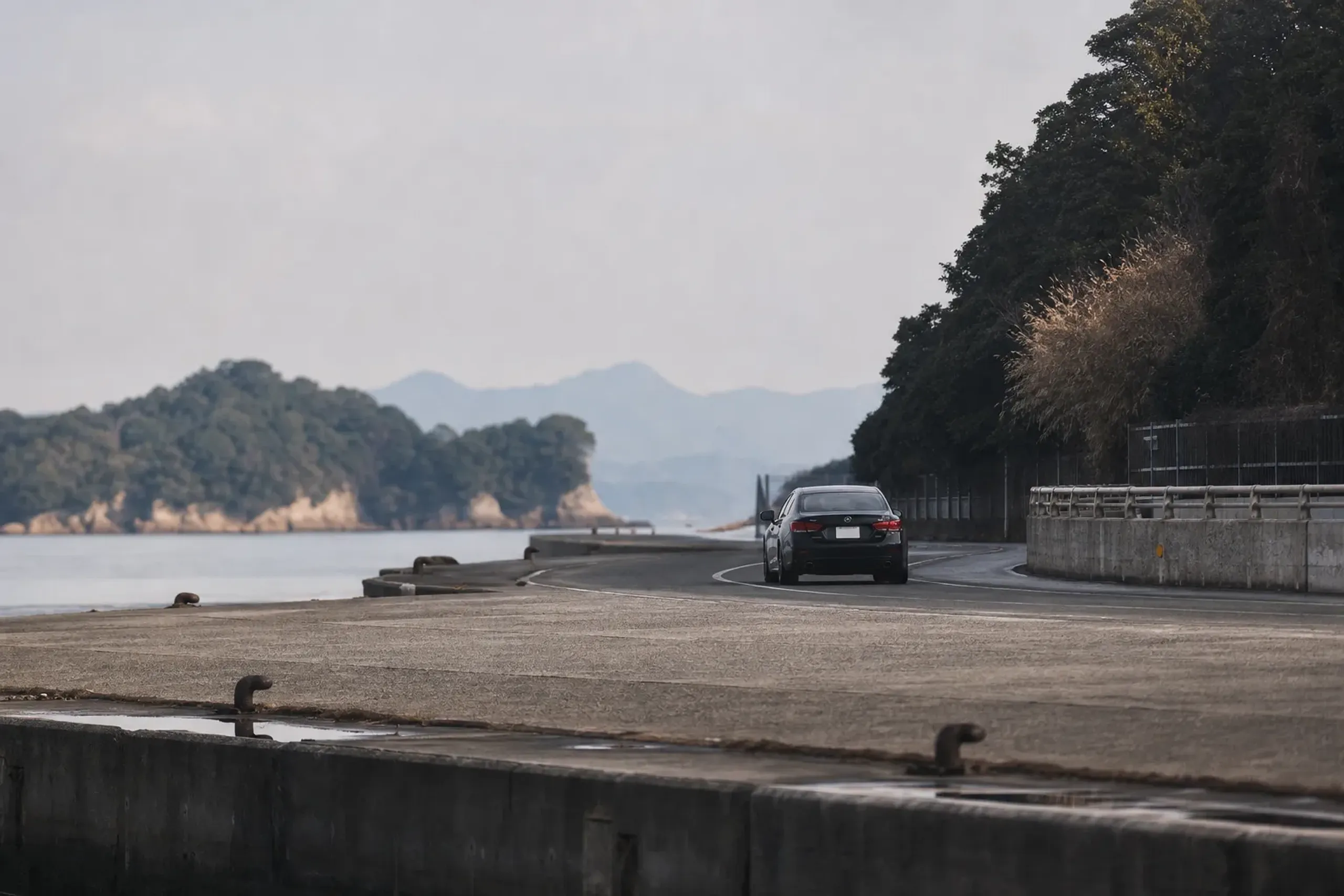 The port berth area of Takamatsu with a car departing toward Matsushima-chō, showing the short coastal drive to the lacquer studio