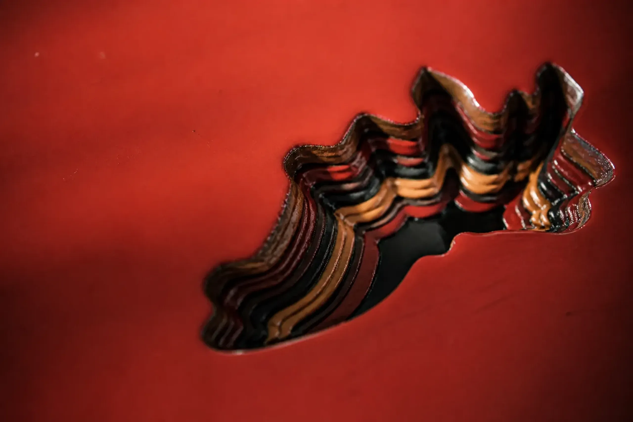 A Chōshitsu lacquer piece carved down through dozens of coloured layers, revealing bands of colour like rock strata in cross-section