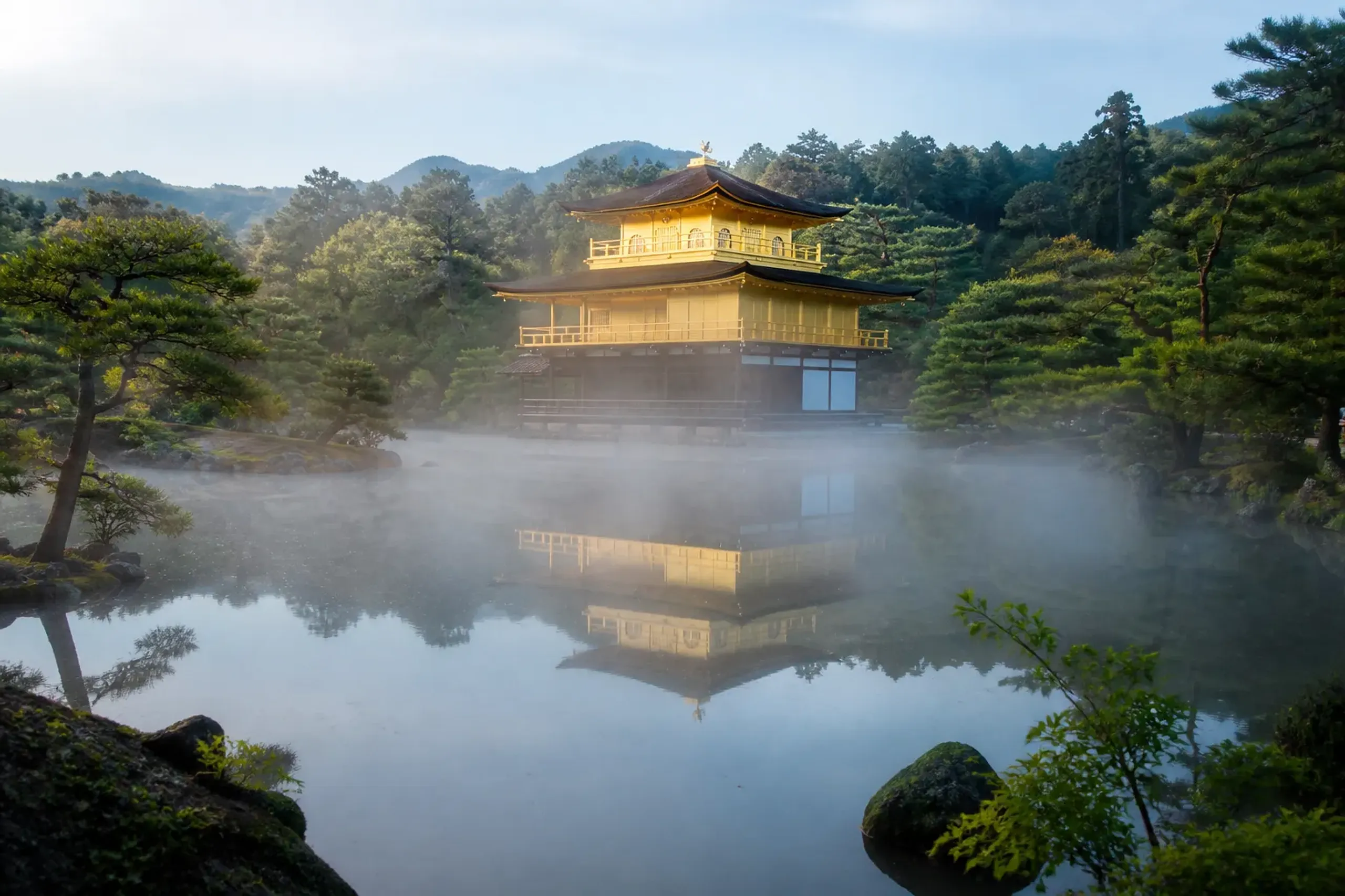 Golden Pavilion Kinkaku-ji reflected in a calm pond in early morning light with few visitors