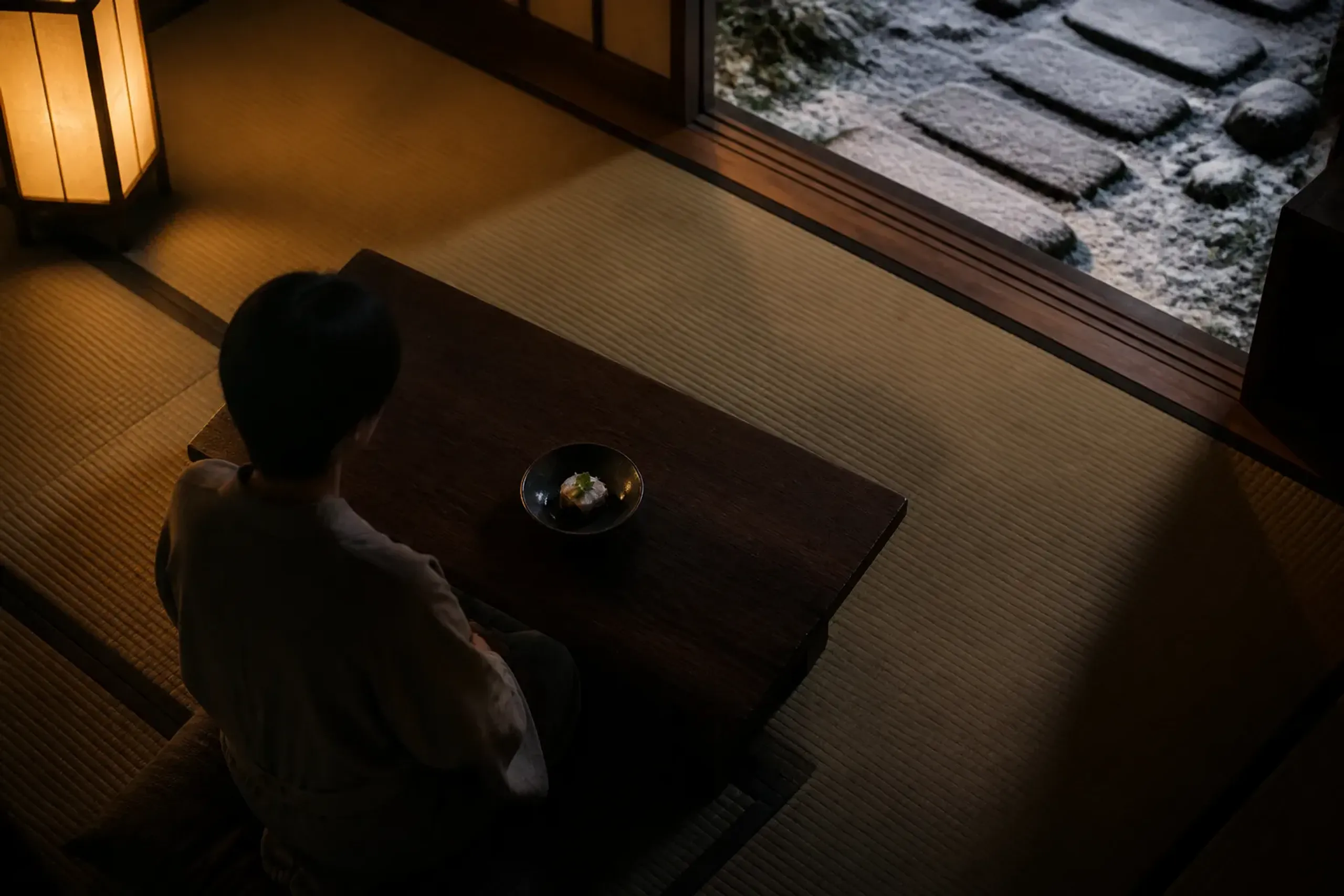 Guest seated on a cushion at a low table with a single kaiseki dish in a tatami room