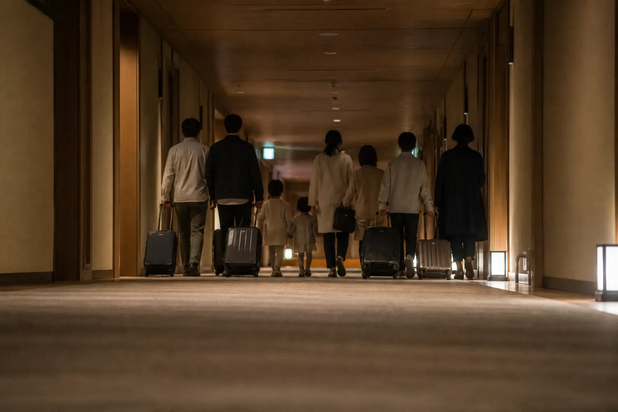A multi-generational family walking down a quiet Japanese hotel corridor at night