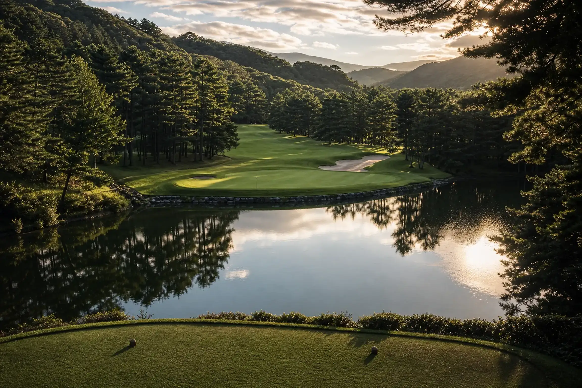 Beautifully maintained golf greens bordered by dense pine forests and a clear lake in Spain.