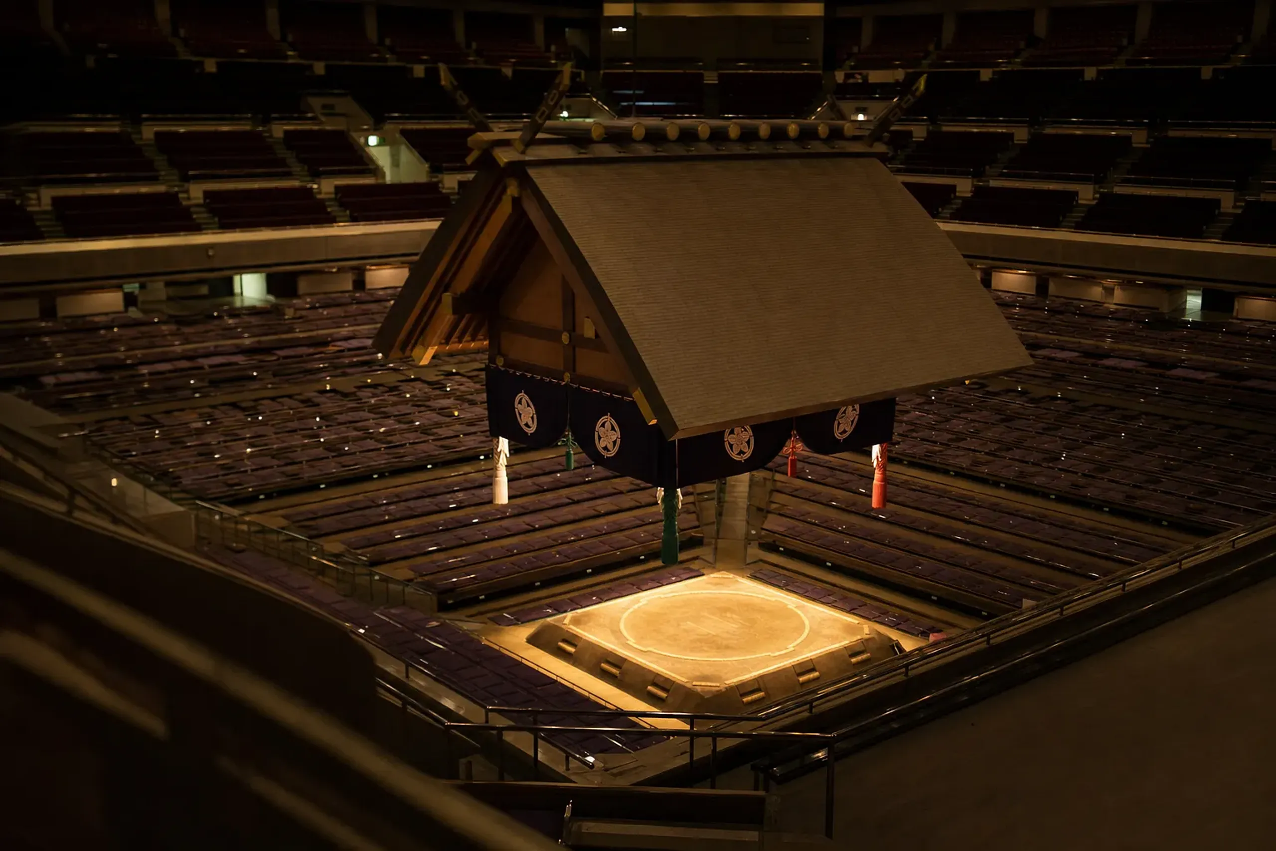 the grand tournament arena interior of the Ryōgoku Kokugikan with its suspended roof canopy over the competition dohyō