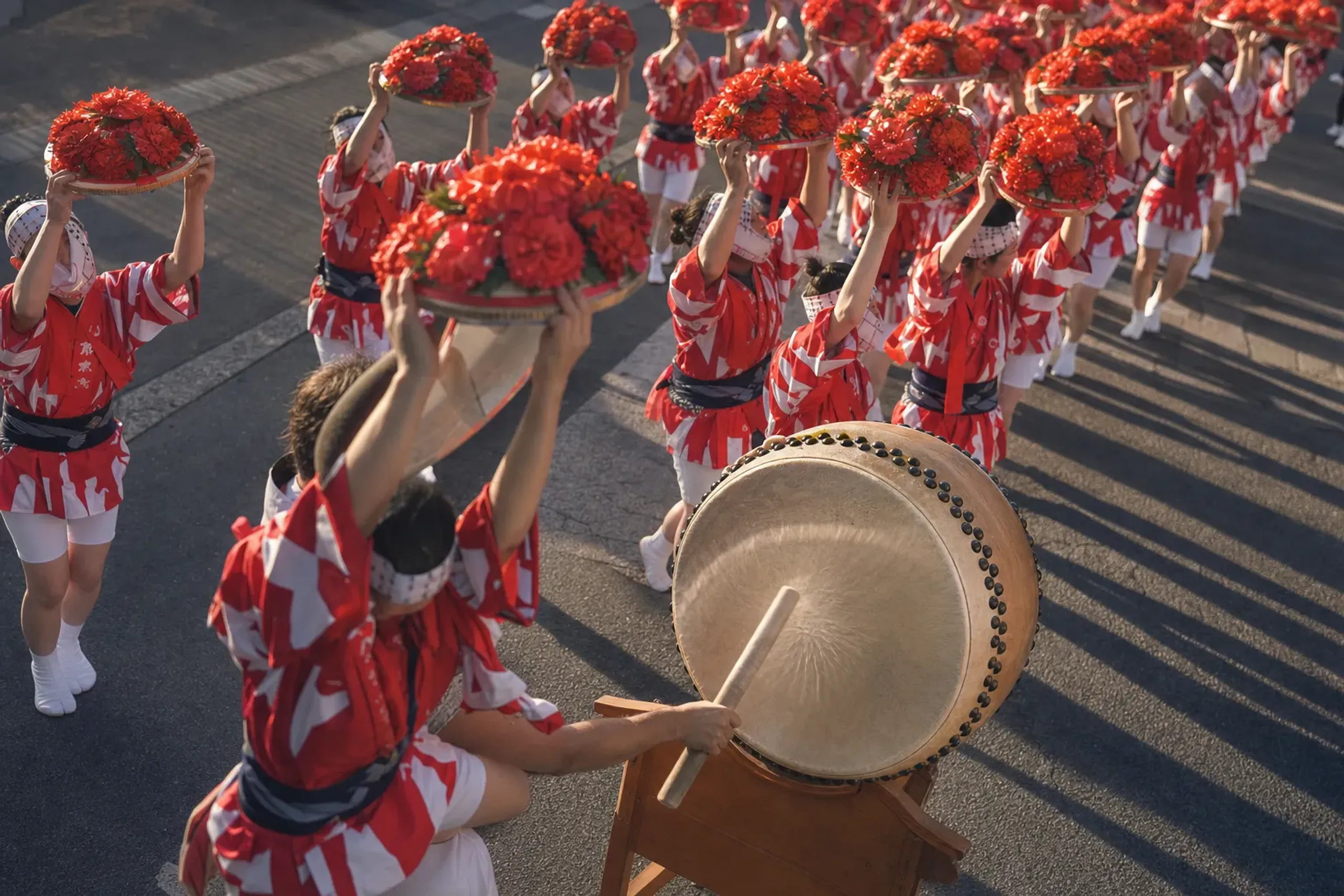 A taiko drum and rows of red safflower hats rising in unison along the Tokamachi stretch of Yamagata's main street during the Hanagasa procession
