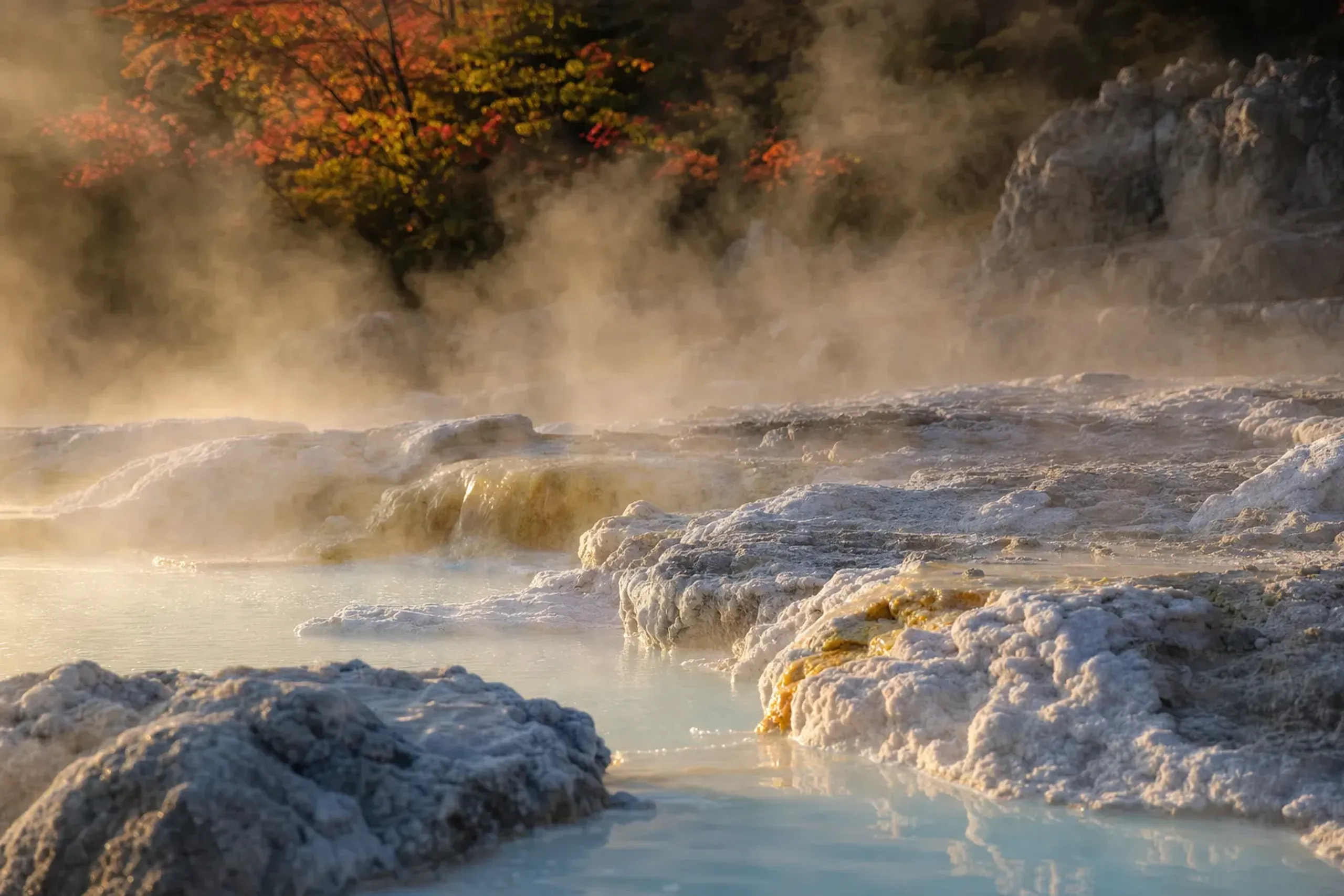 Steaming sulfuric hot spring water pooling over pale mineral-crusted stone at Zaō Onsen