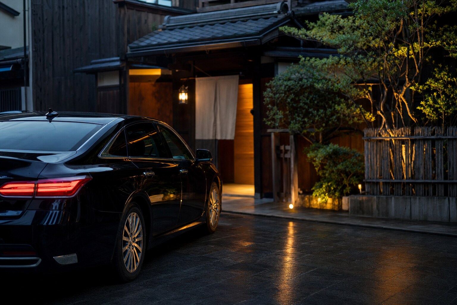 Black luxury chauffeur vehicle parked outside a traditional Japanese restaurant at dusk
