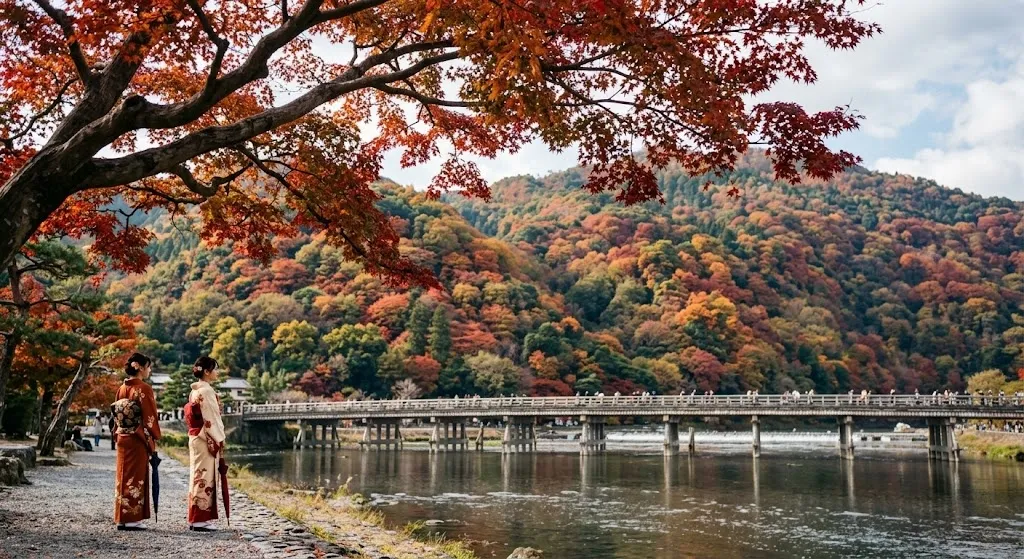 A scenic view of Kyoto's historic Togetsukyo Bridge spanning the Hozu River, with a majestic mountain covered in vibrant autumn foliage in the background.