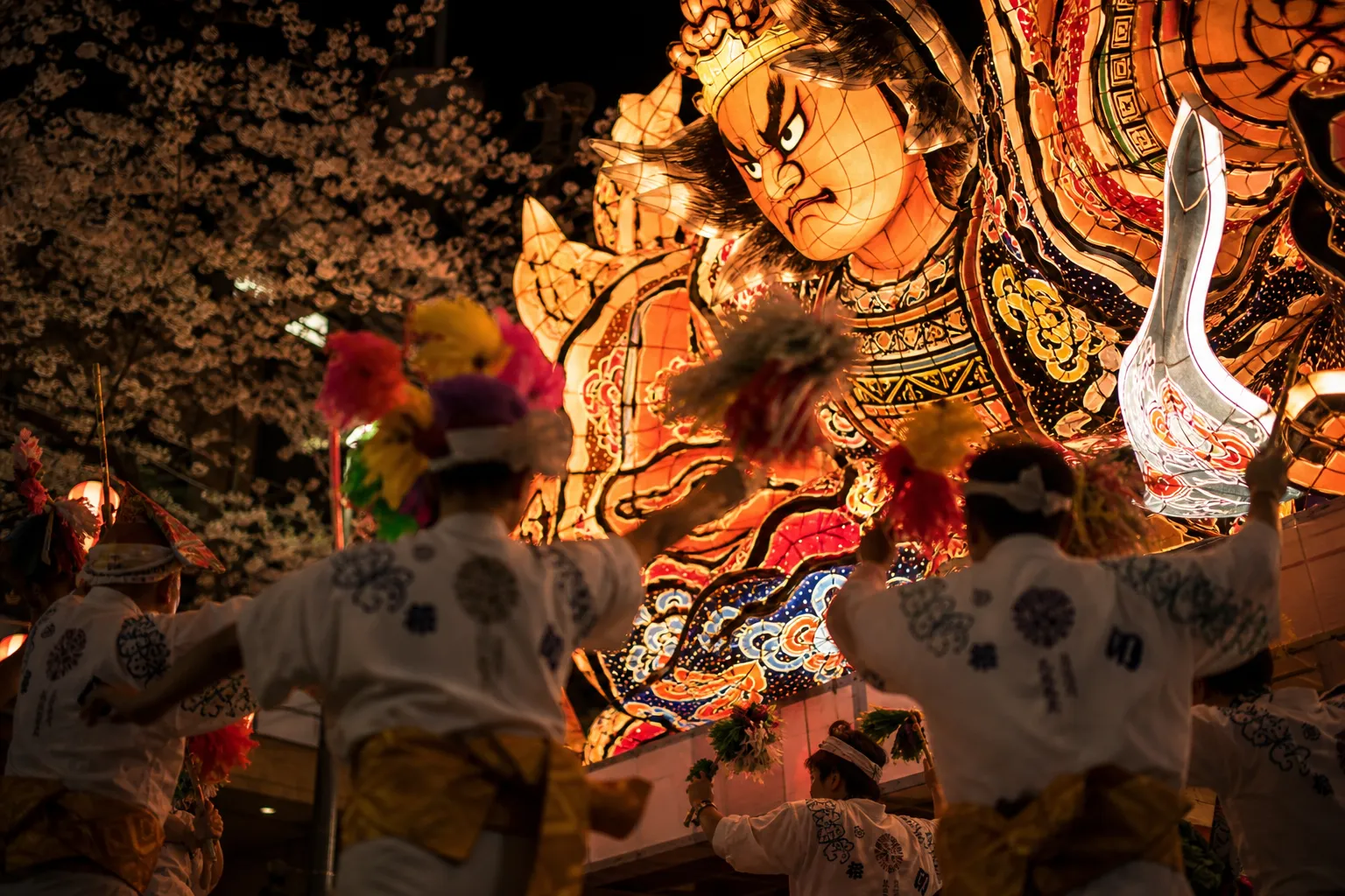 Giant glowing Nebuta paper float of a warrior moving through Aomori at night